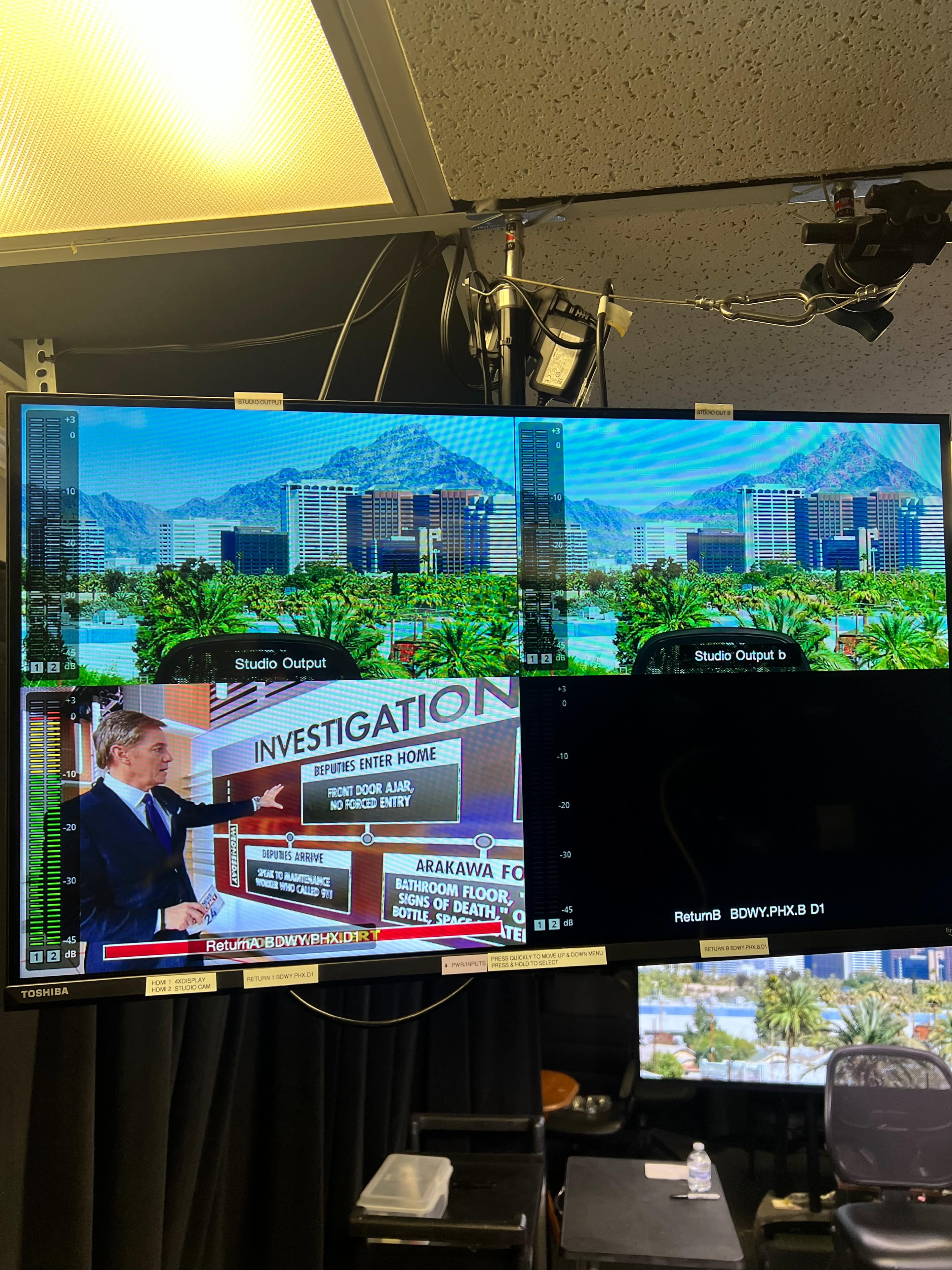 The image shows a split-screen display with one side featuring a news anchor in a studio and the other side showing a scenic view of a city with mountains in the background.