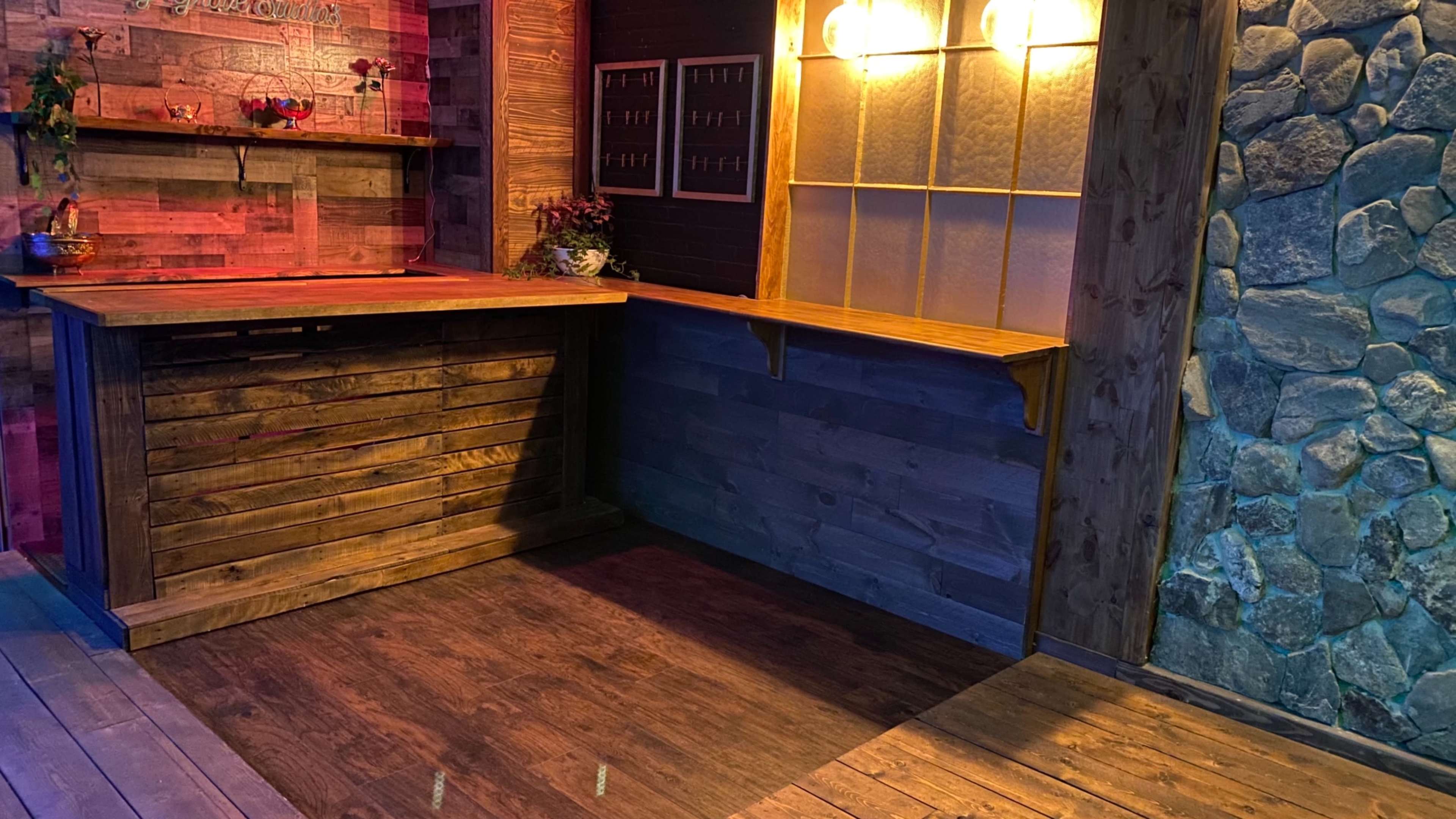 A wooden reception area with a counter, shelves, and a stone wall.