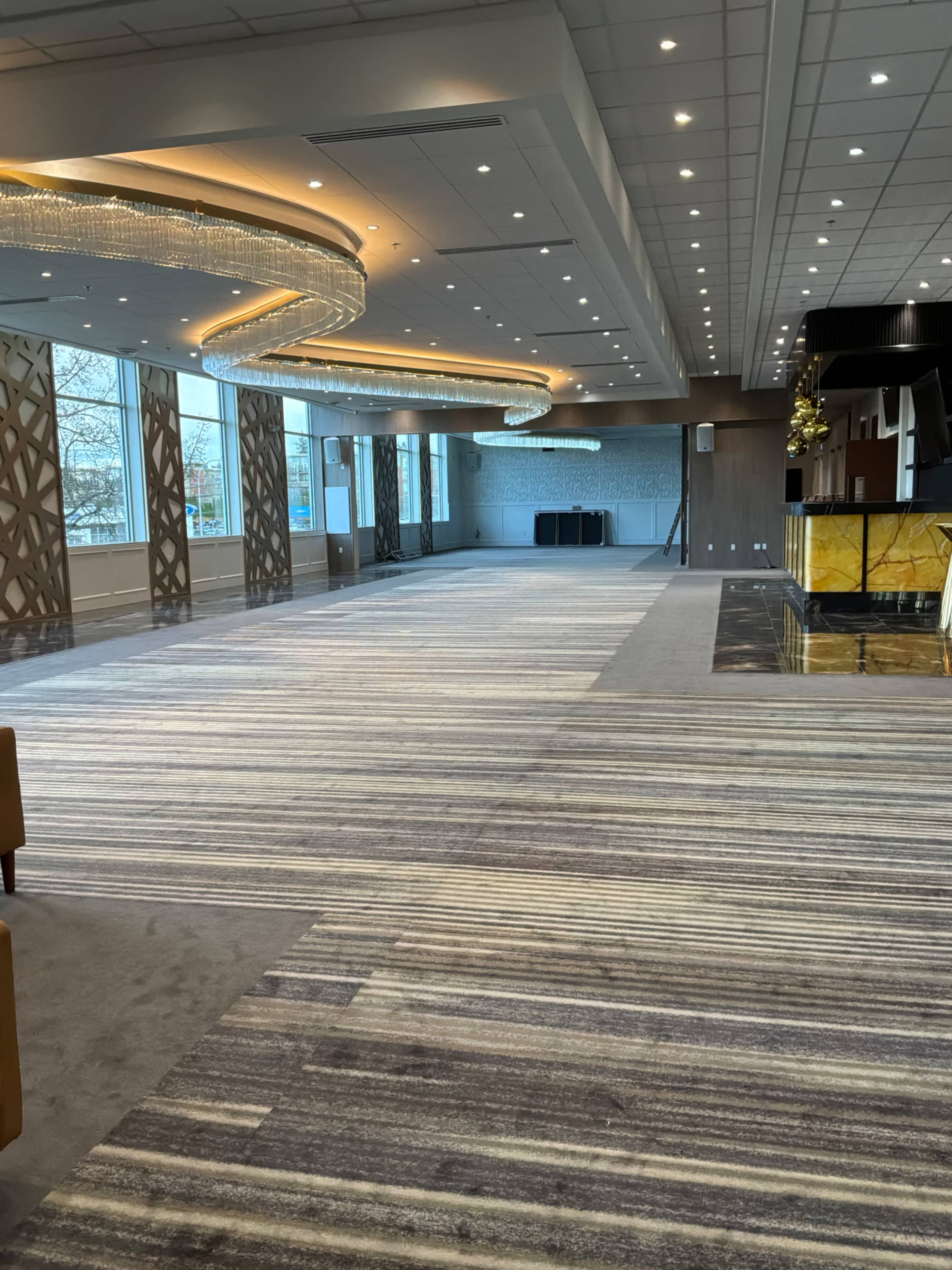 The image shows a spacious, elegantly designed event space with modern lighting and carpeted flooring.