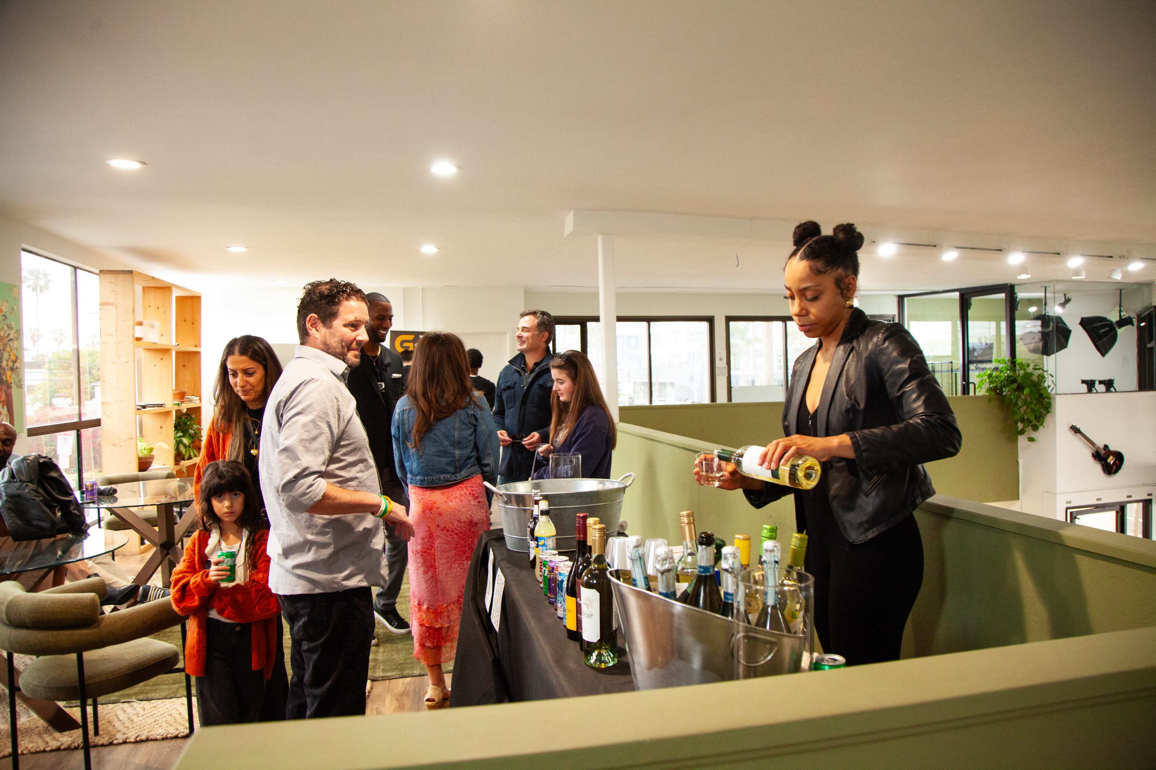 A group of people socialize around a table with beverages in a modern indoor space.
