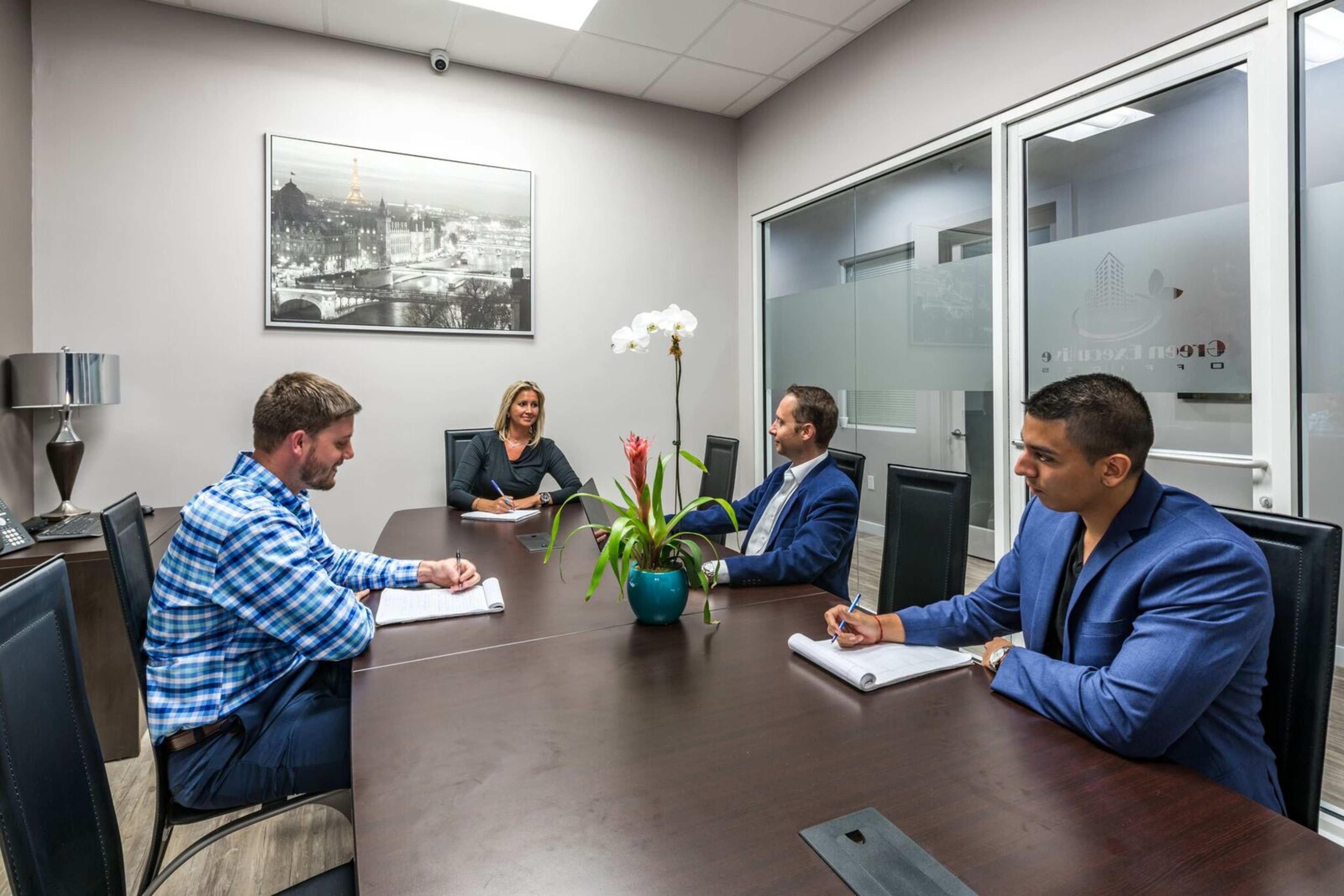 Four professionals engage in a meeting around a conference table in a modern office.