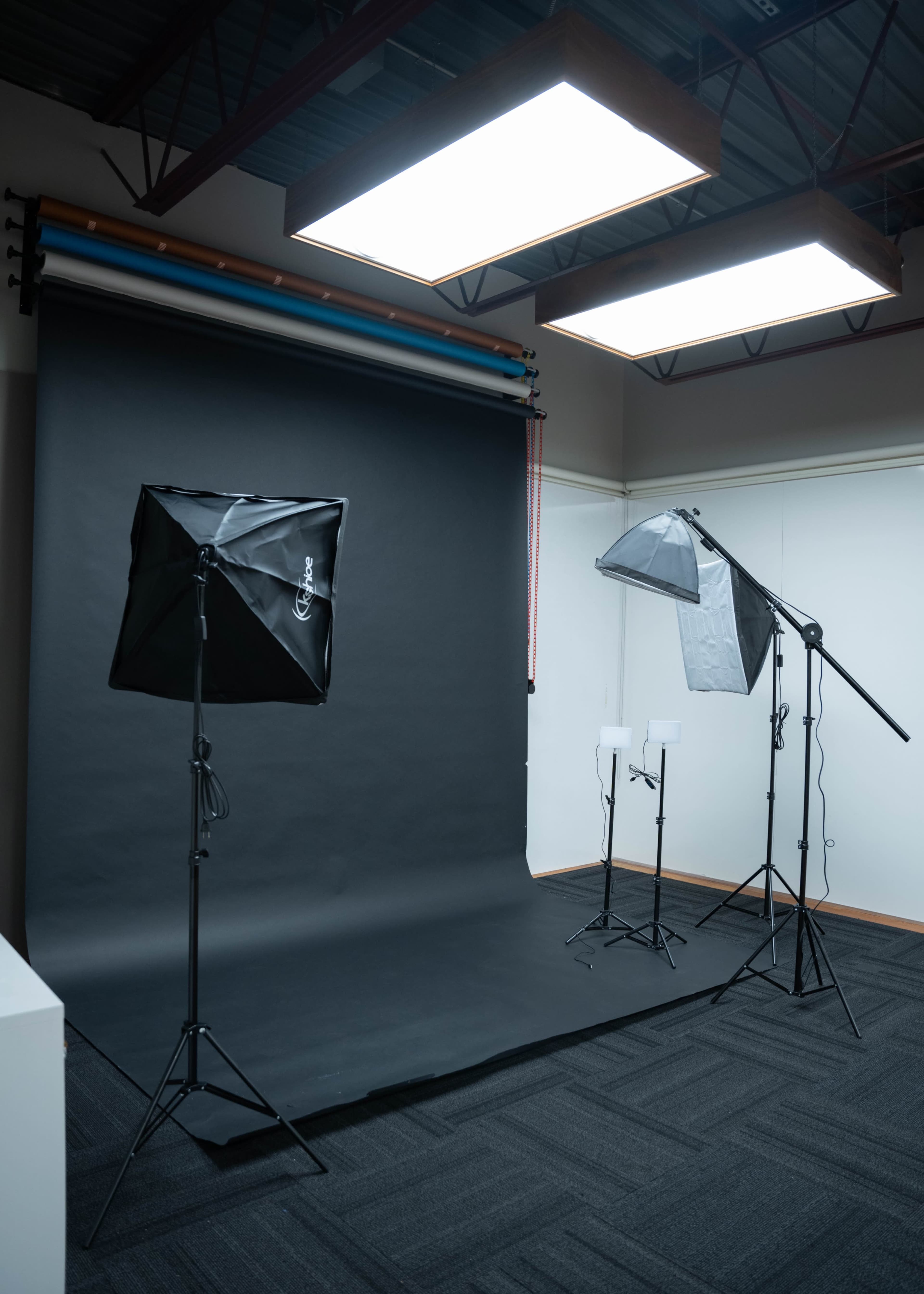 The image shows a photography studio equipped with multiple light fixtures and a black backdrop.