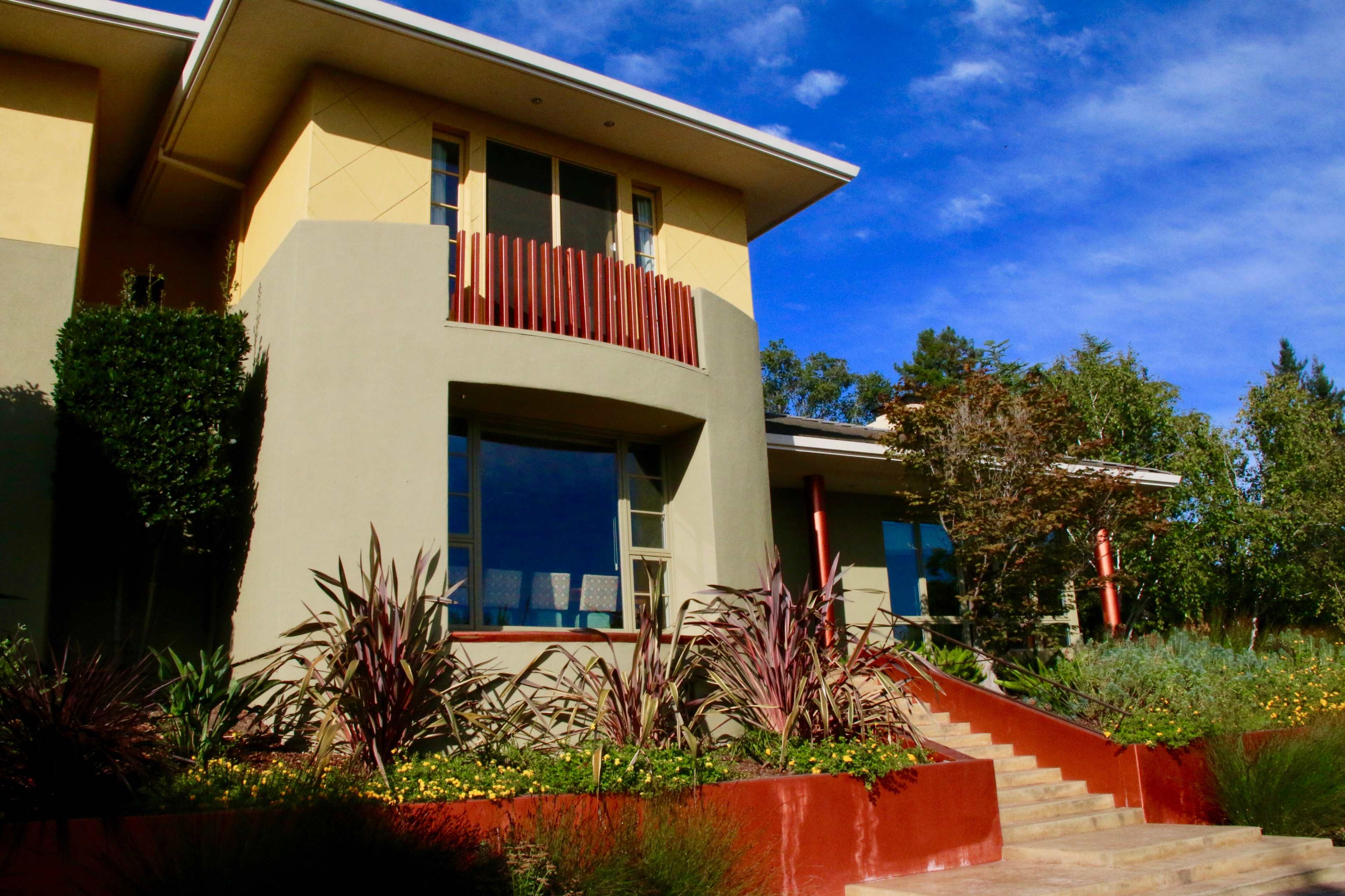 A modern two-story house with a landscaped front garden and steps leading to the entrance.