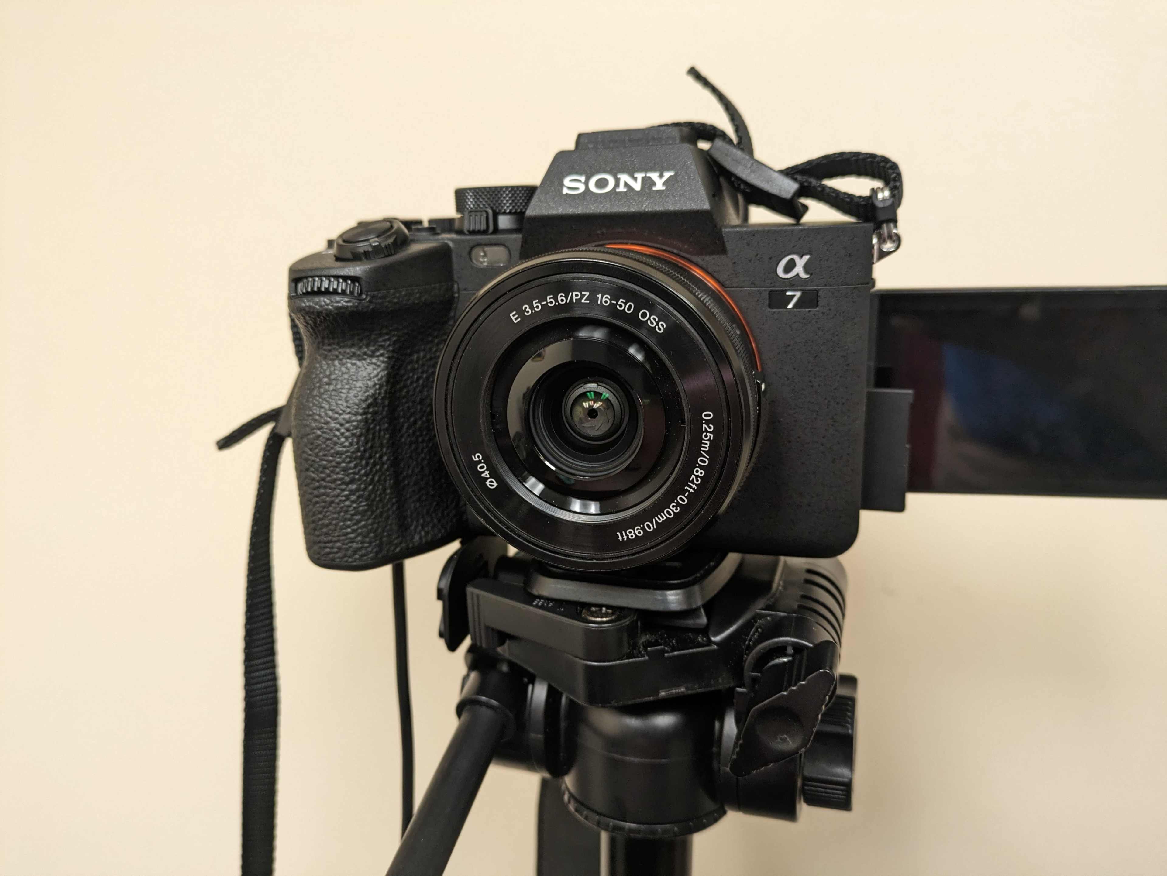 A Sony Alpha 7 camera is mounted on a tripod with a visible lens and a small display screen.