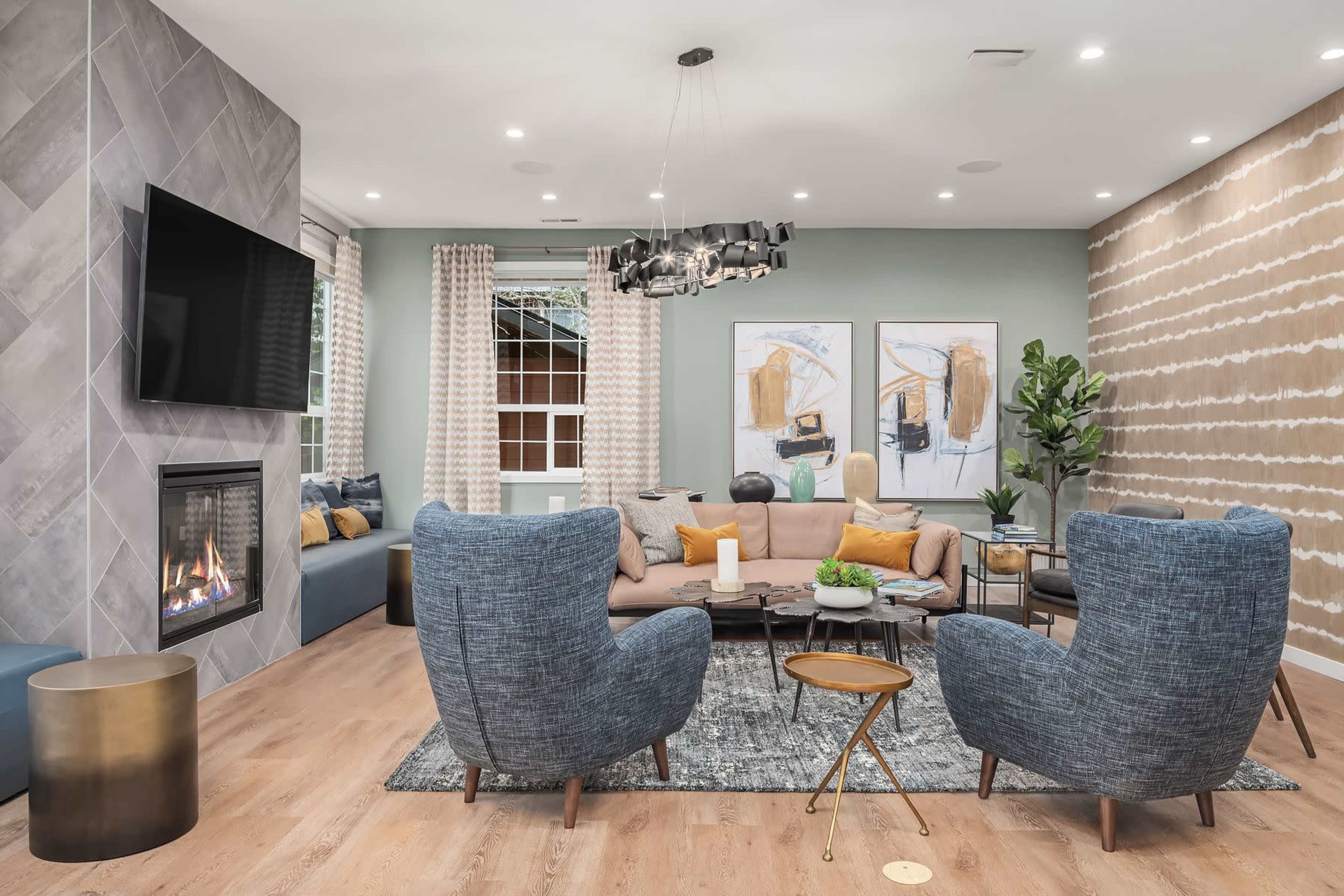 A modern living room featuring a cozy sofa, two large armchairs, a contemporary coffee table, and a wall-mounted television above a fireplace.