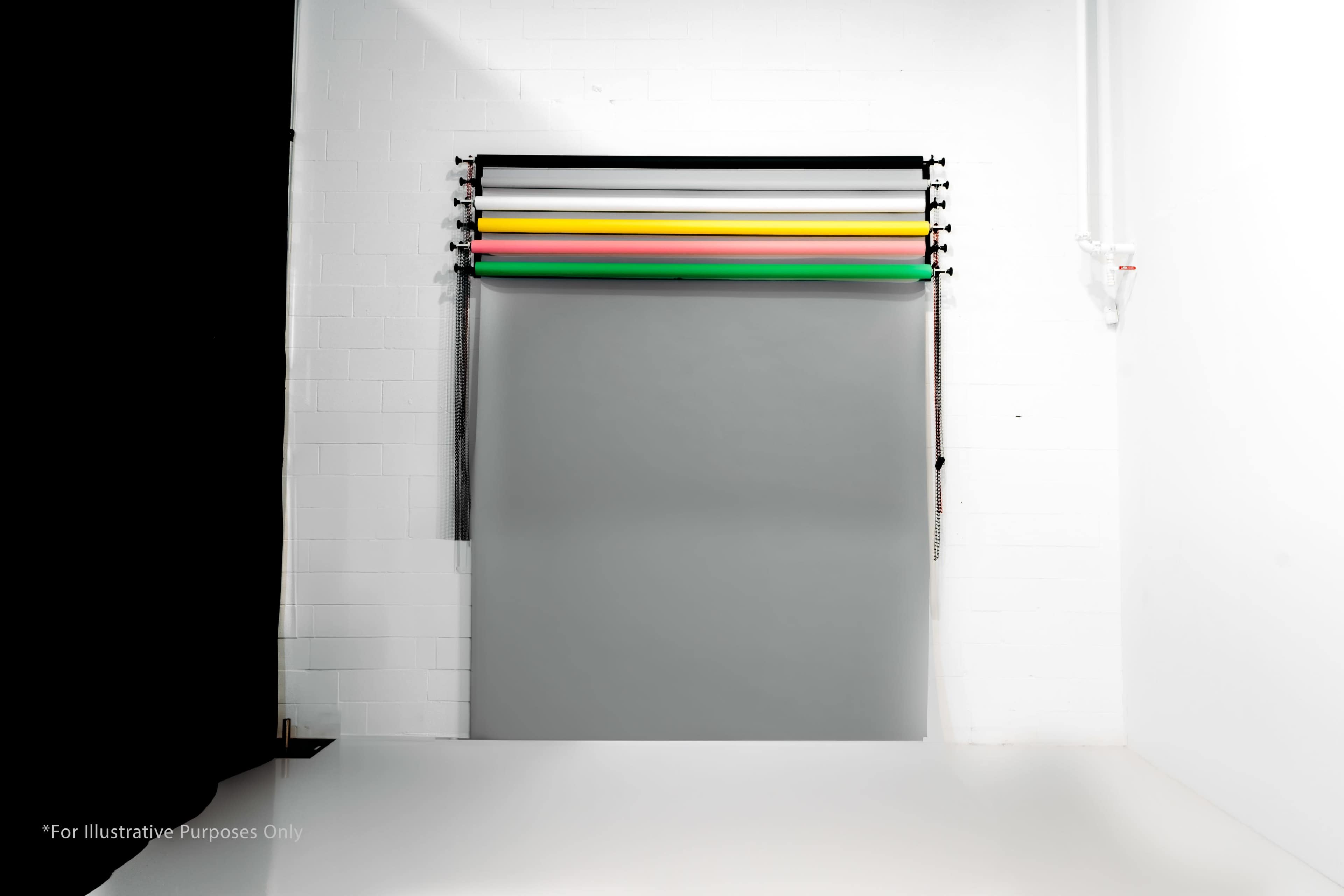 A studio setting with a gray background and several colored backdrop rolls arranged horizontally above it.