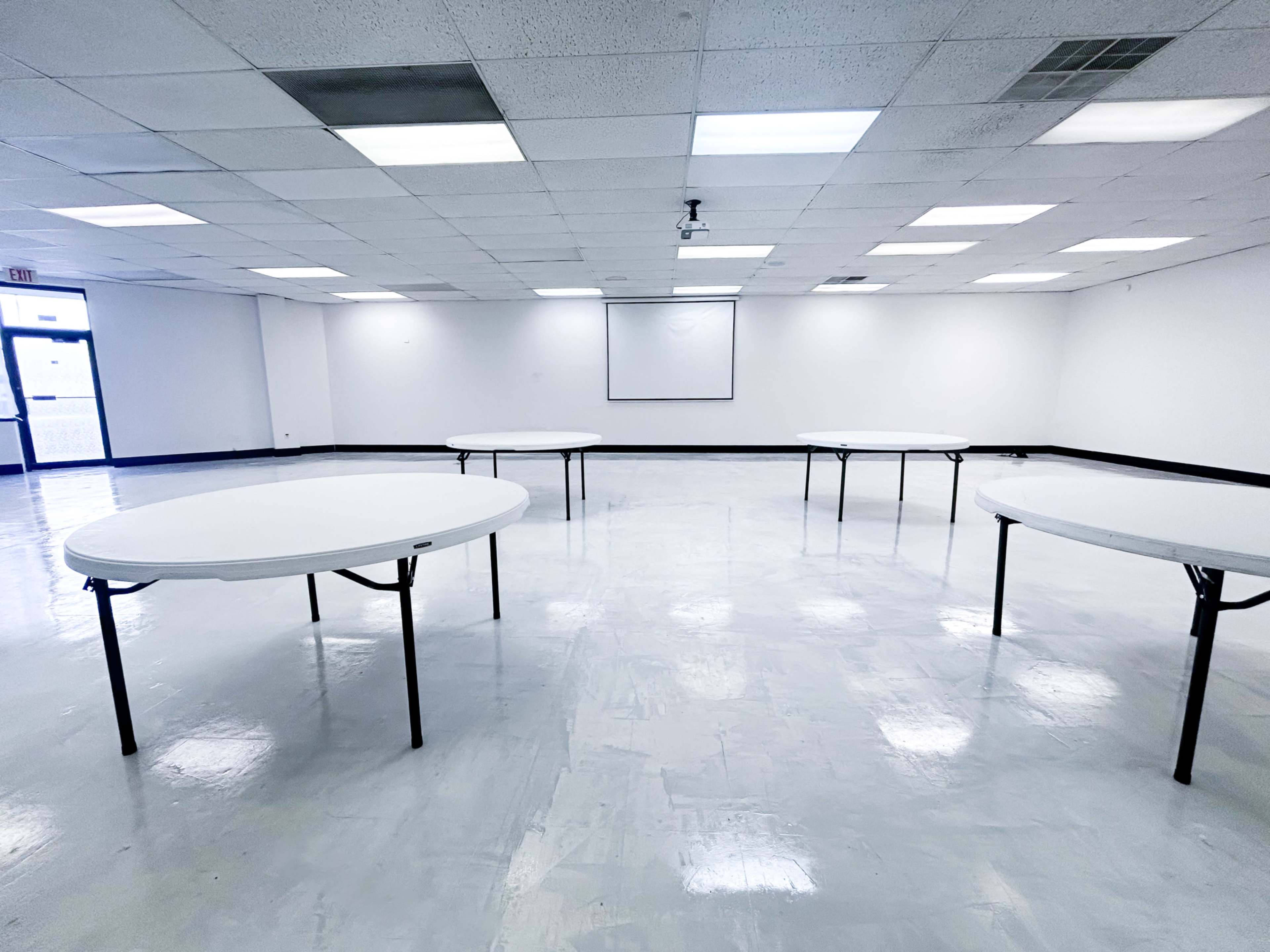 A large, empty room with several round tables arranged in a spacious, well-lit area.