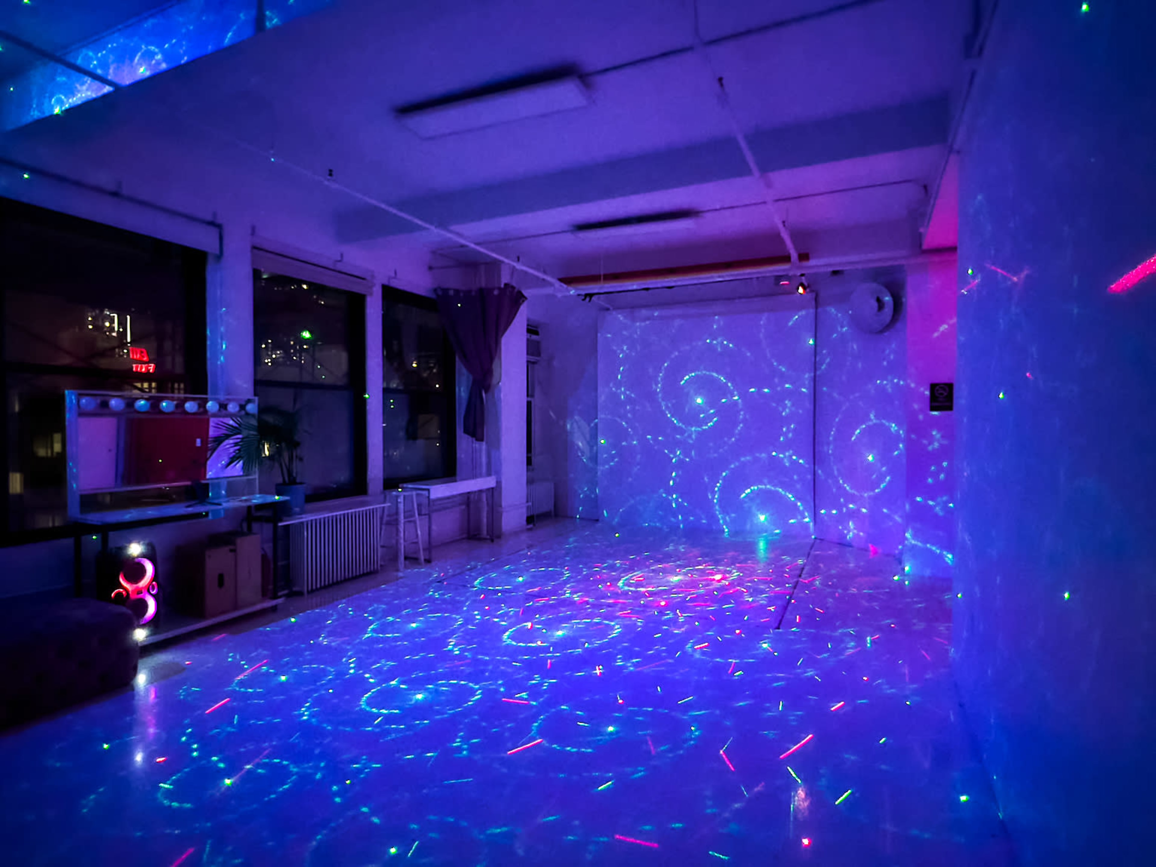 The image shows a dimly lit room with swirling blue and purple laser projections on the walls and floor.