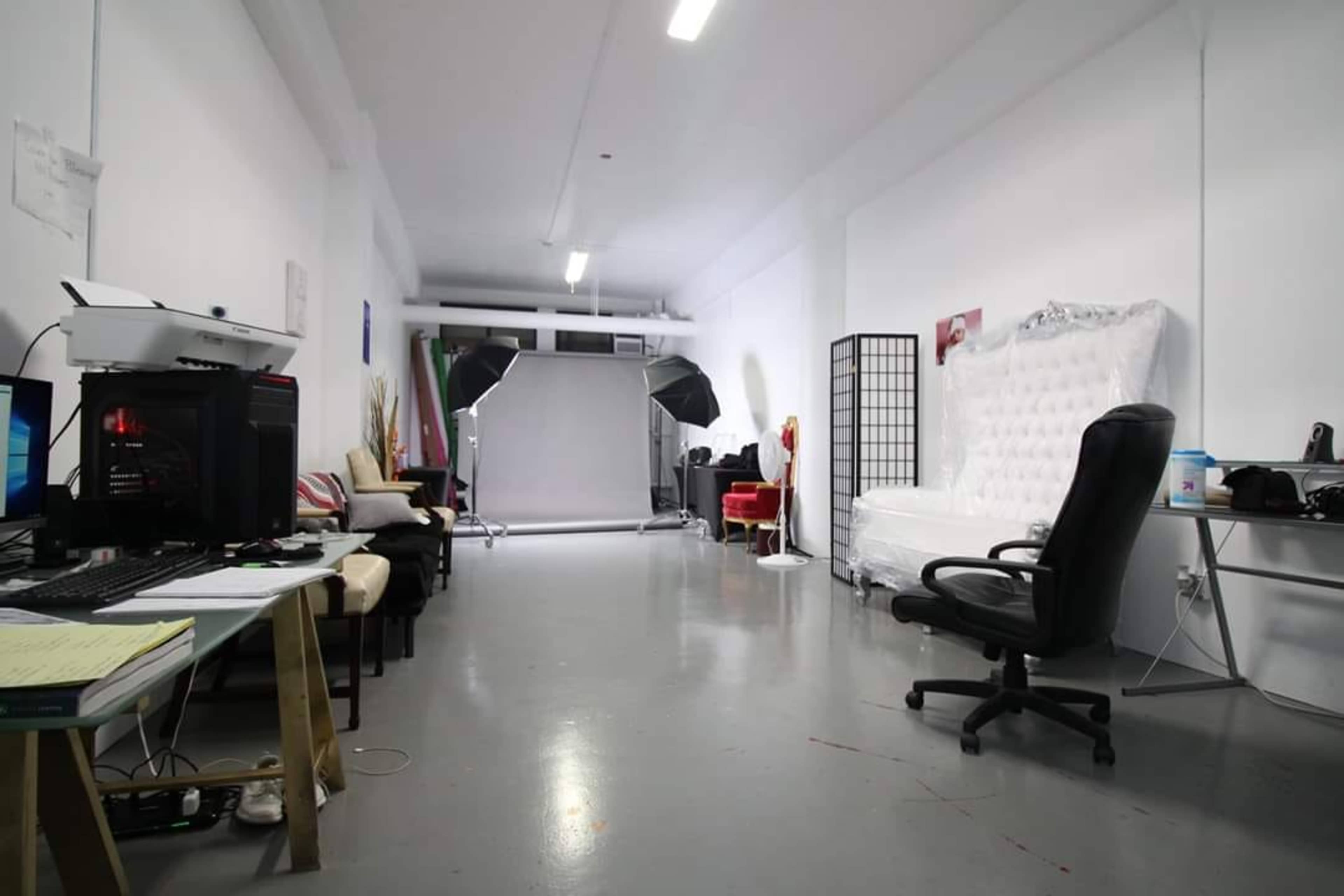 A studio space with various seating areas, a backdrop setup, and equipment for photography, including a computer workstation.