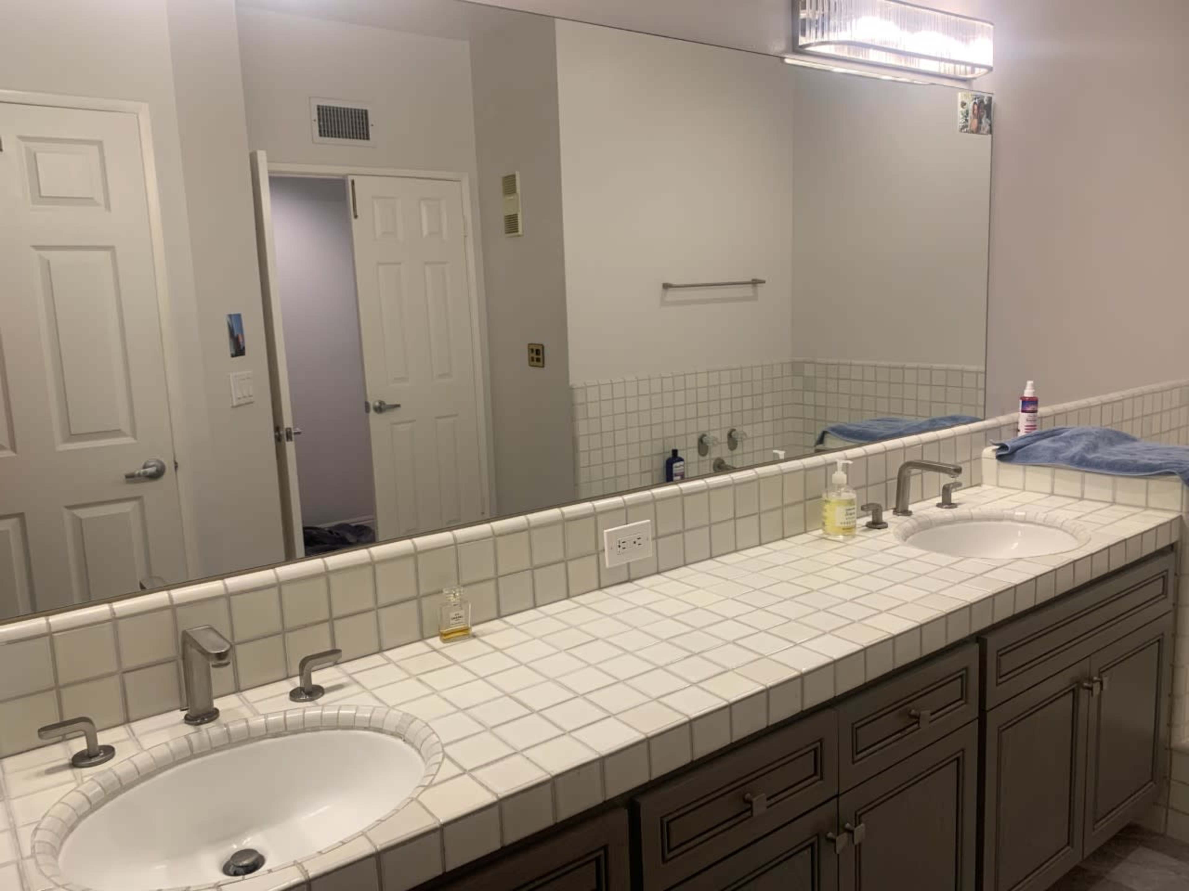 A bathroom with a double sink vanity, a large mirror, and a towel placed on the countertop.