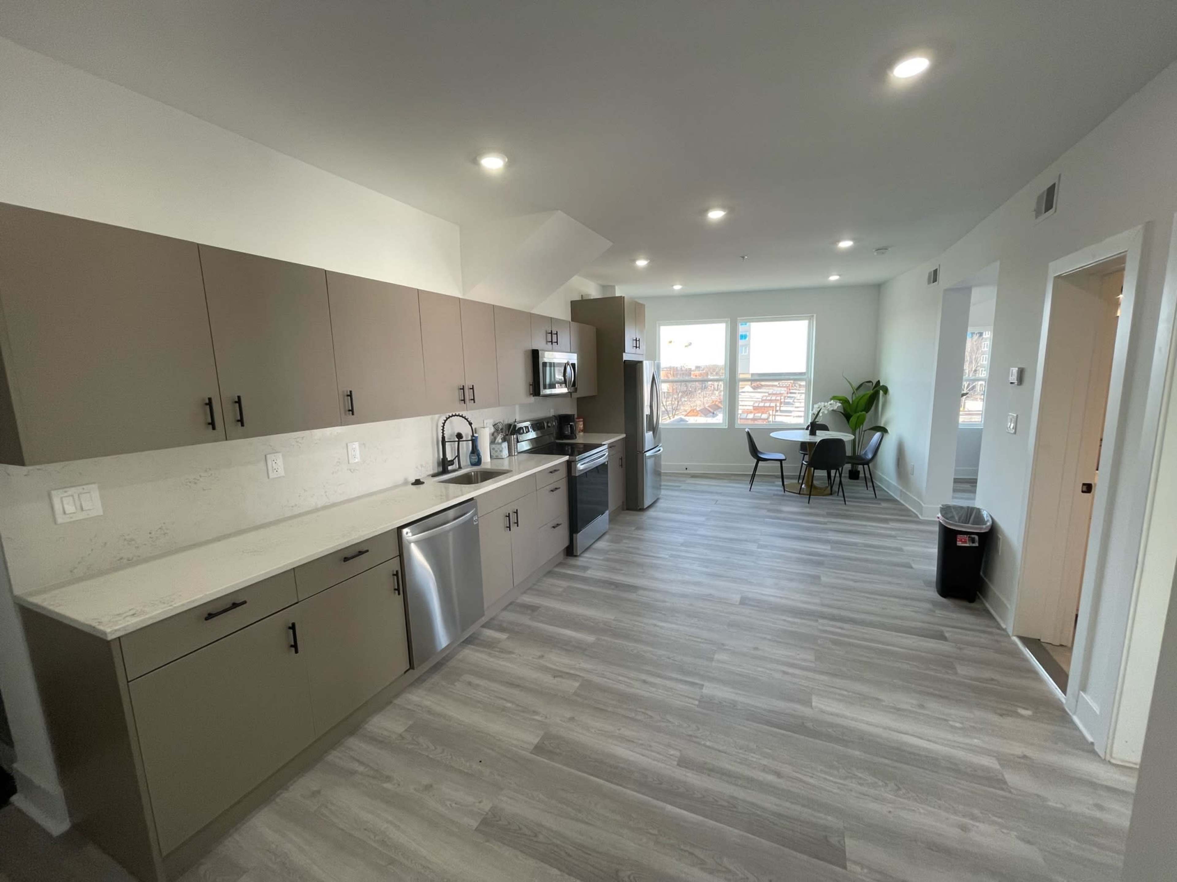 A modern kitchen with light-colored cabinets, stainless steel appliances, and a dining area featuring a round table and chairs.