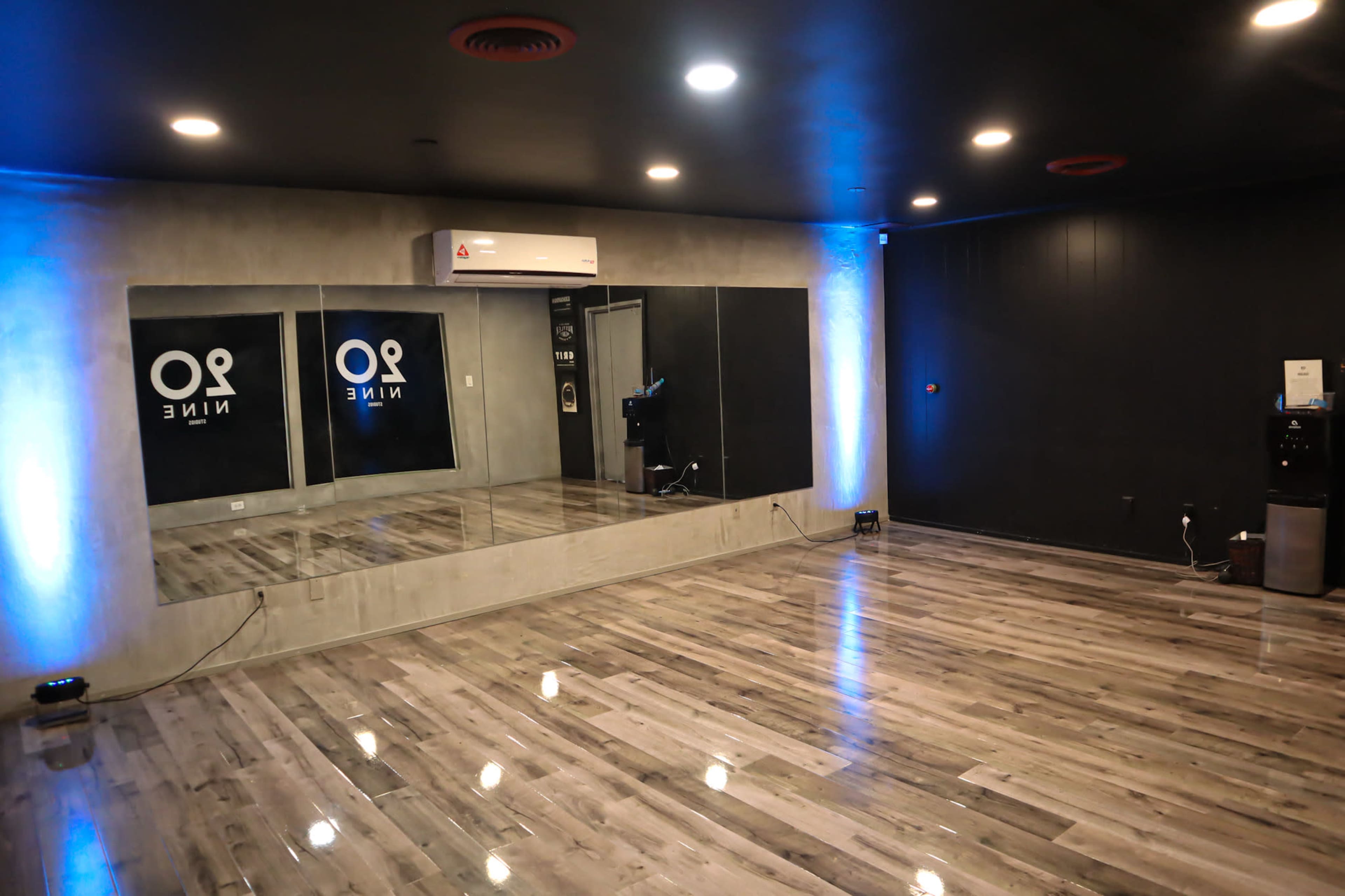 A practice room with wooden flooring, mirrored walls, and soft lighting.