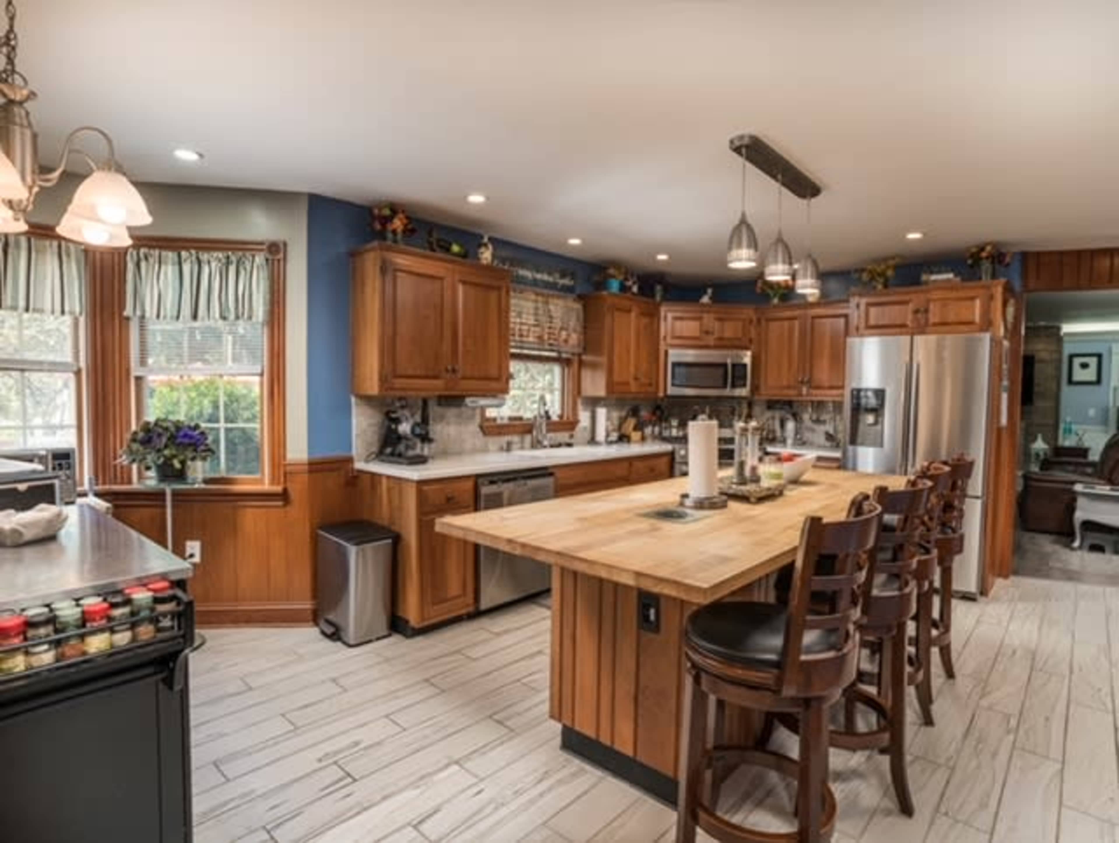 A spacious kitchen features wooden cabinetry, a large island with seating, and modern appliances.