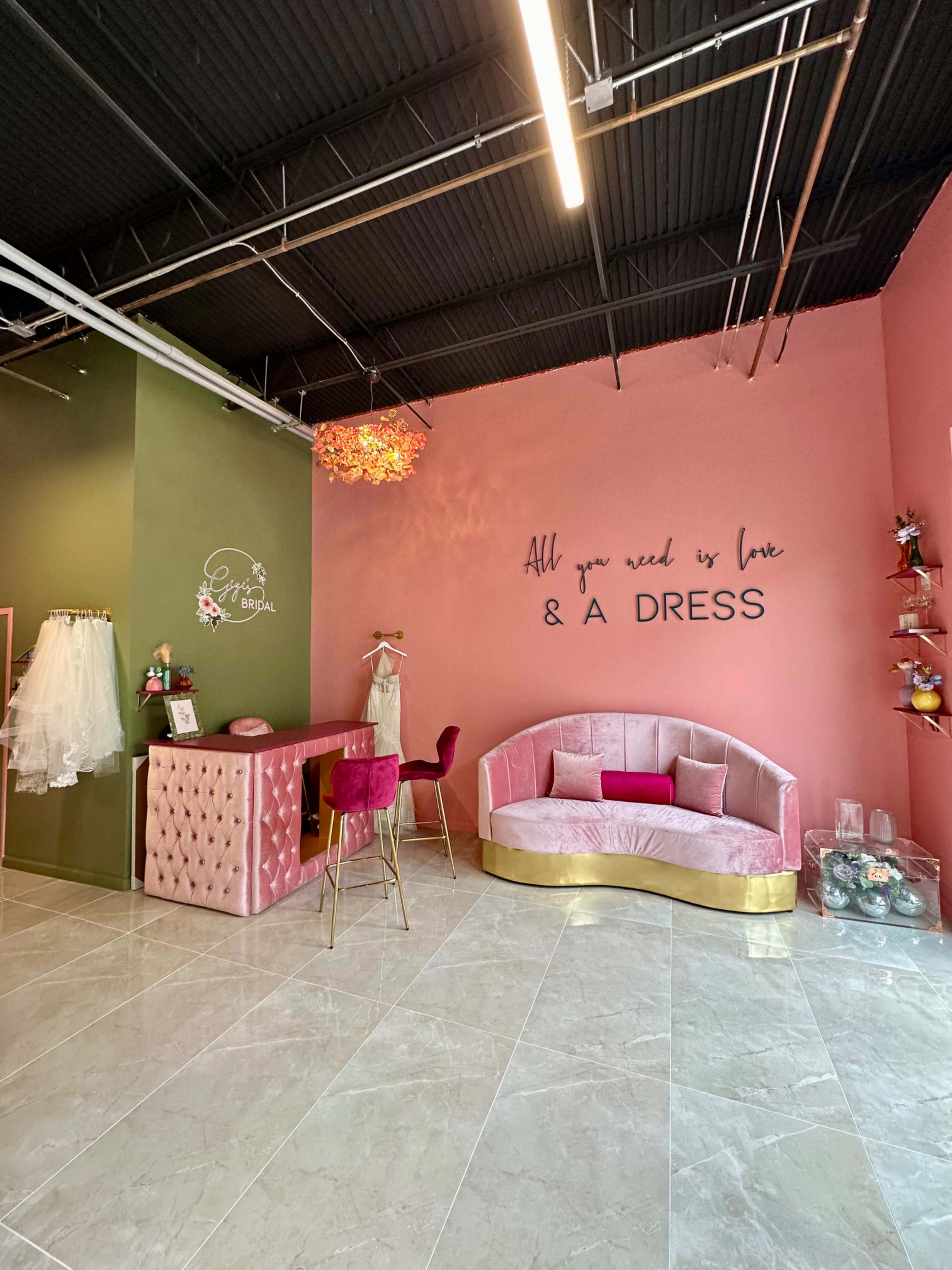 The image shows a boutique interior with a pink and green color scheme, featuring a seating area, a reception desk, and wedding dresses displayed on the wall.