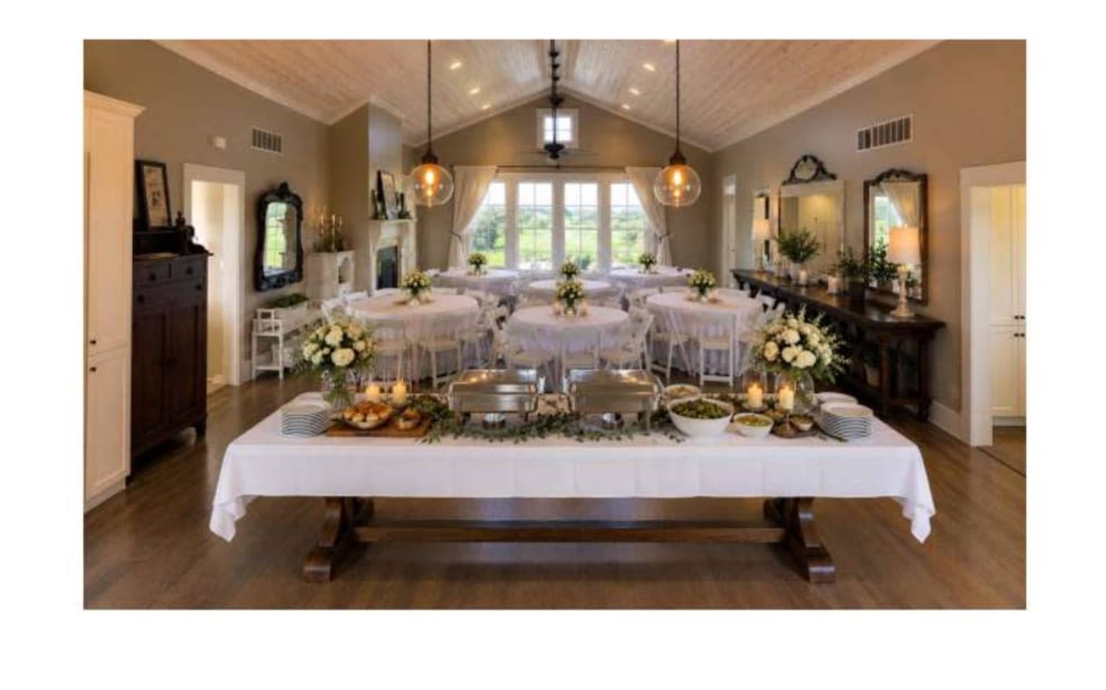 The image shows an elegantly arranged banquet hall with tables set for an event and a buffet table displaying food options in the foreground.