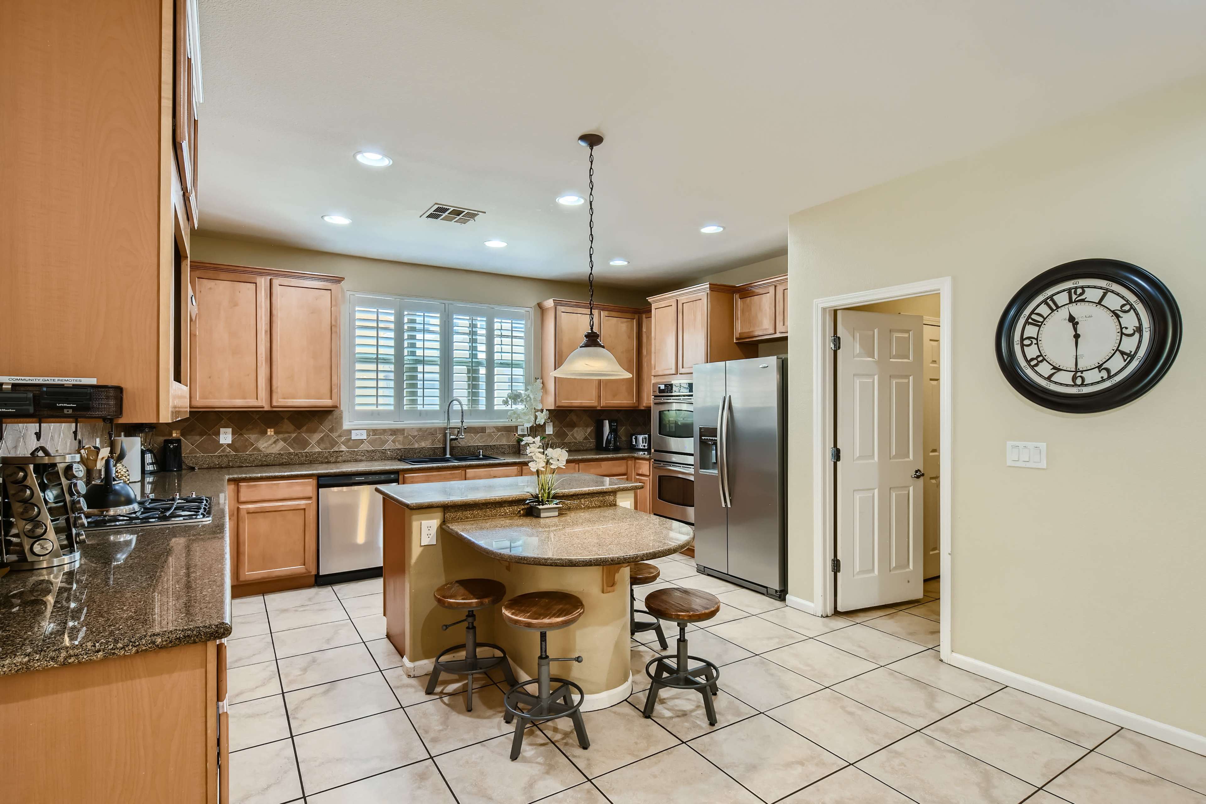 A modern kitchen with wooden cabinets, a central island with bar stools, and stainless steel appliances.