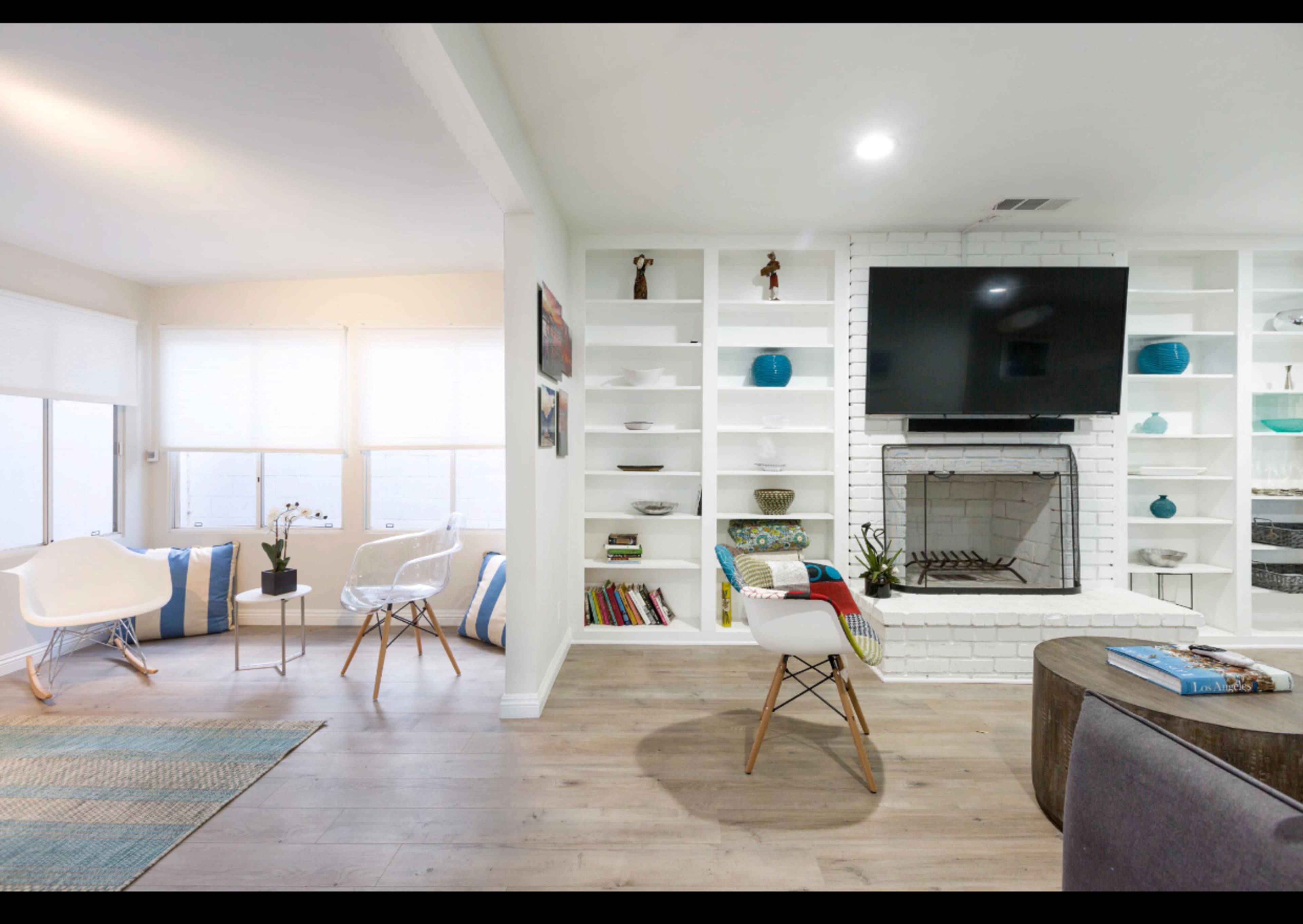A modern living room features a white brick fireplace, built-in shelves with decorative items, and a seating area with chairs and a coffee table.
