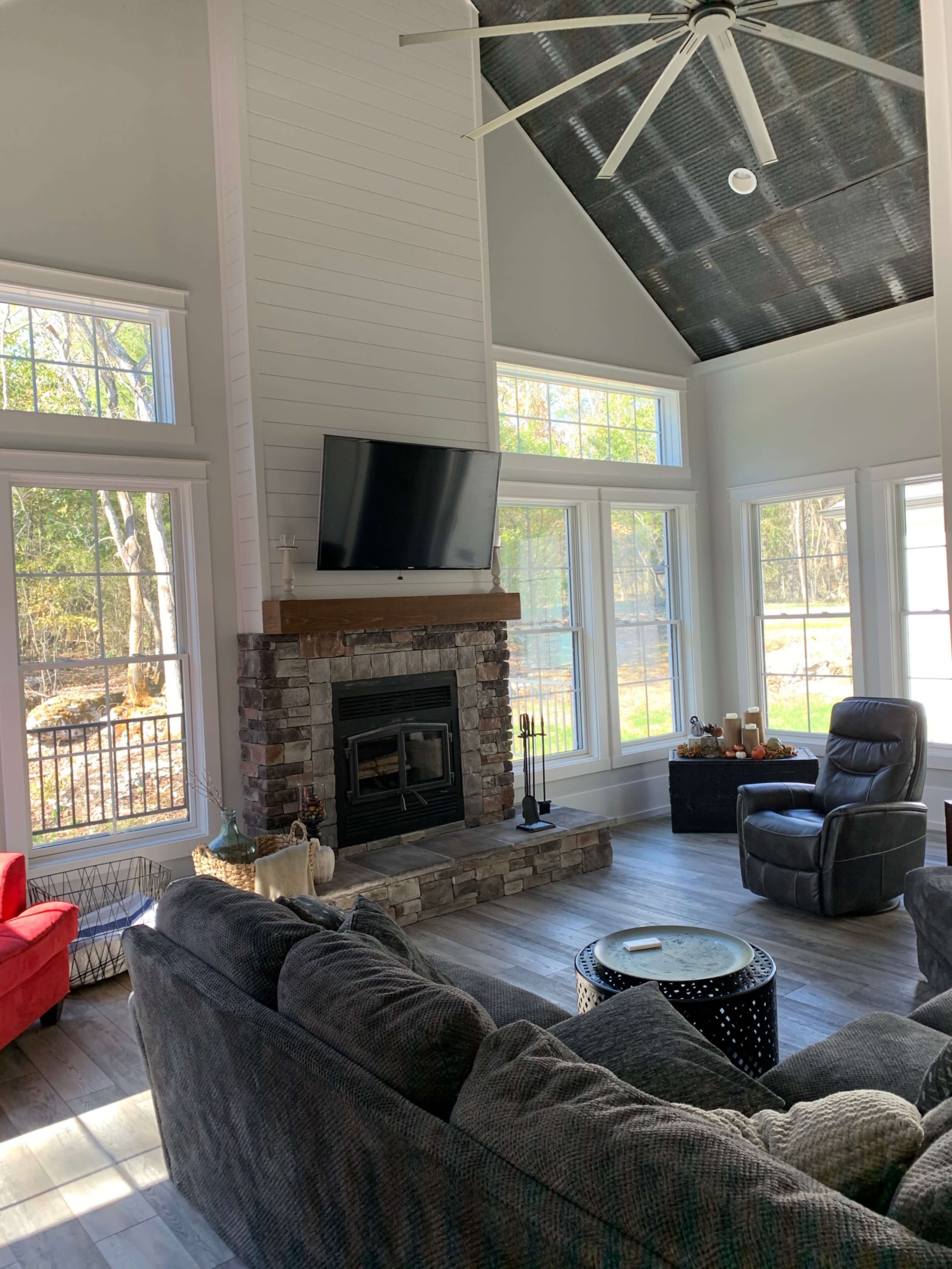 The spacious living room features a stone fireplace, large windows, and comfortable seating arranged around a coffee table.