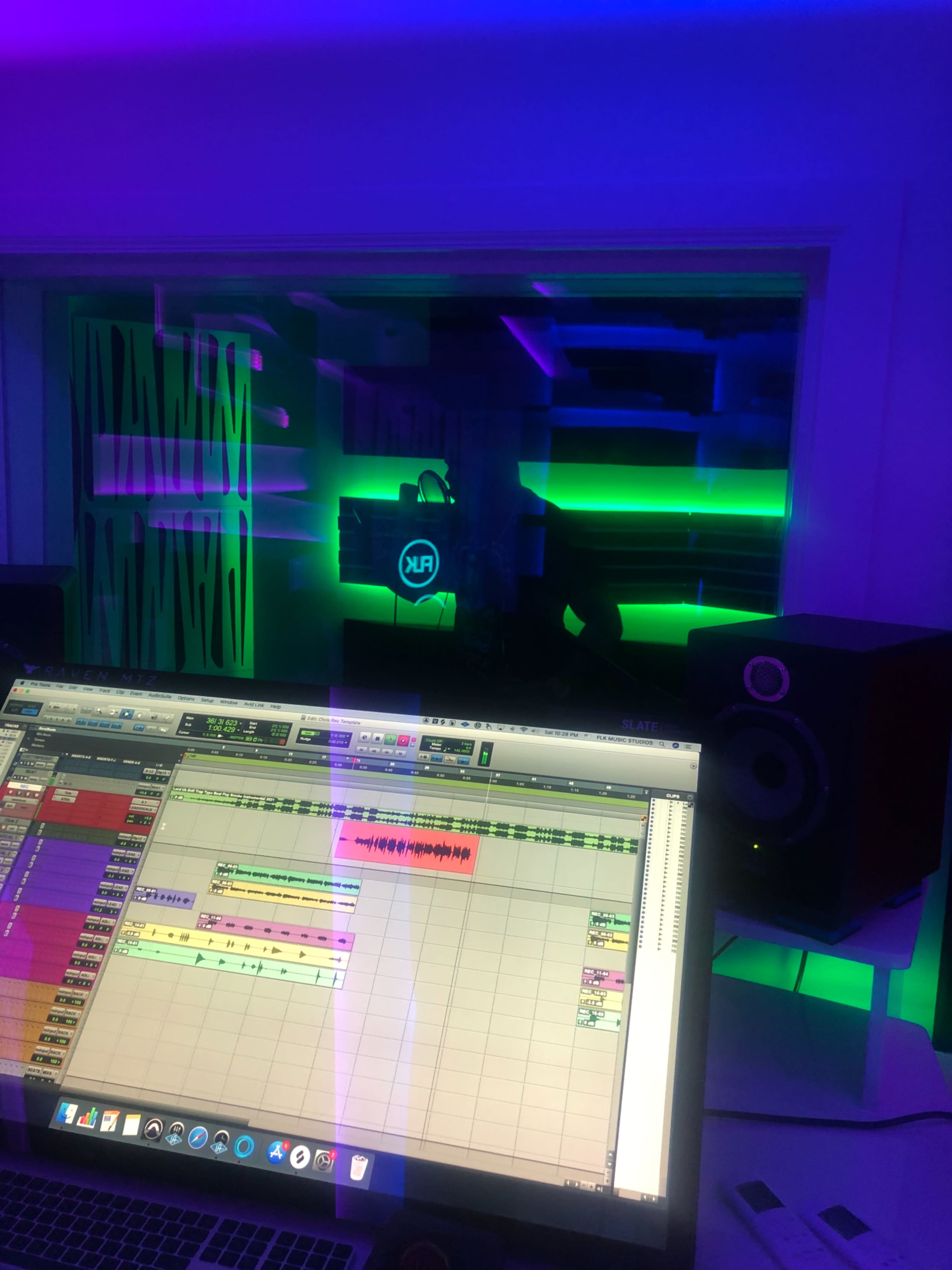 The image shows a music studio with a computer displaying audio editing software and colorful ambient lighting in the background.