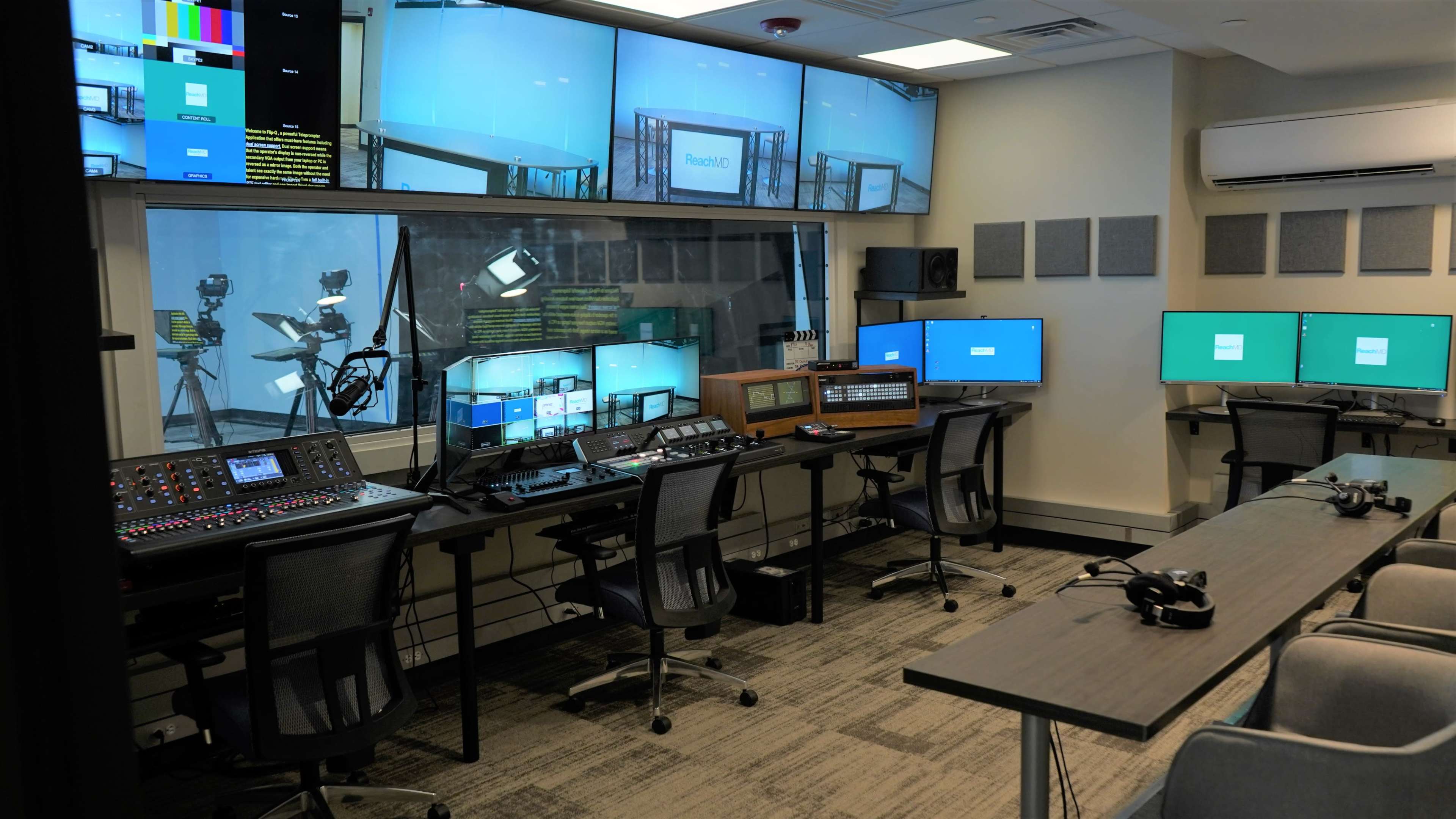 A modern television control room equipped with multiple monitors, editing stations, and broadcasting equipment arranged around a central workspace.