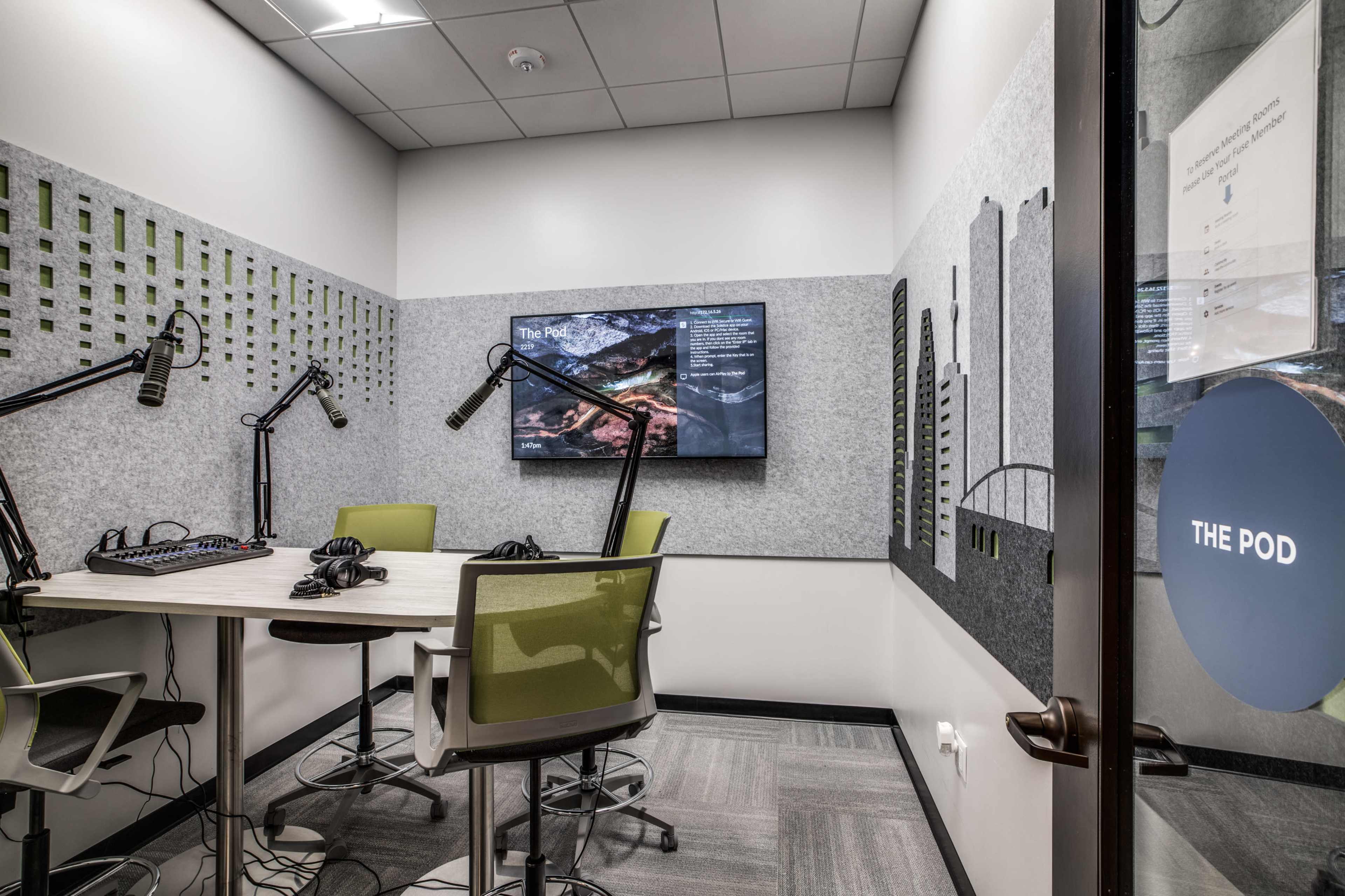 A small meeting room equipped with a large screen, microphones, and seating for discussions.