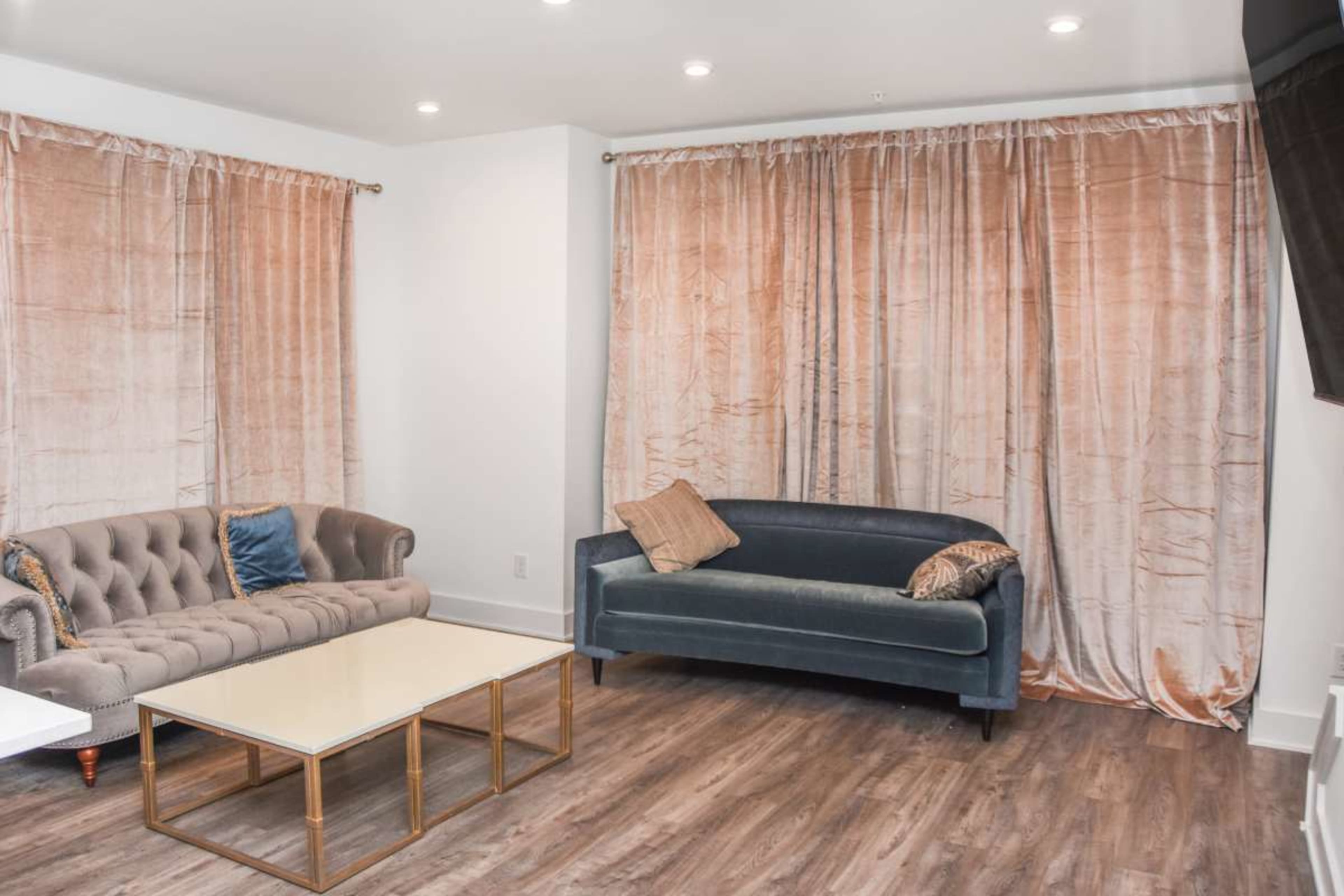 The image shows a room with two sofas, a coffee table, and large curtains draping over the windows.