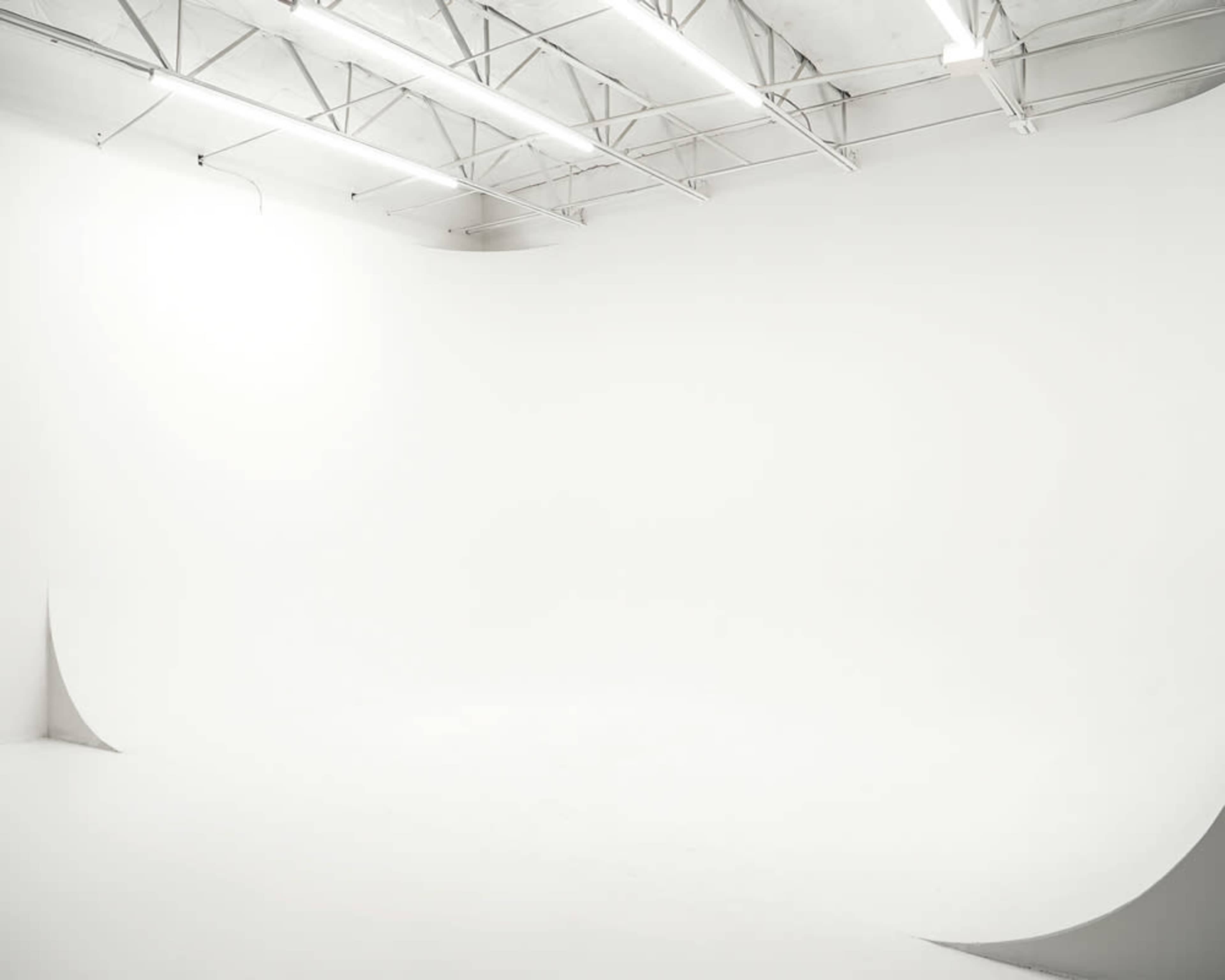 A spacious, well-lit photography studio with a seamless white backdrop and minimalist design.