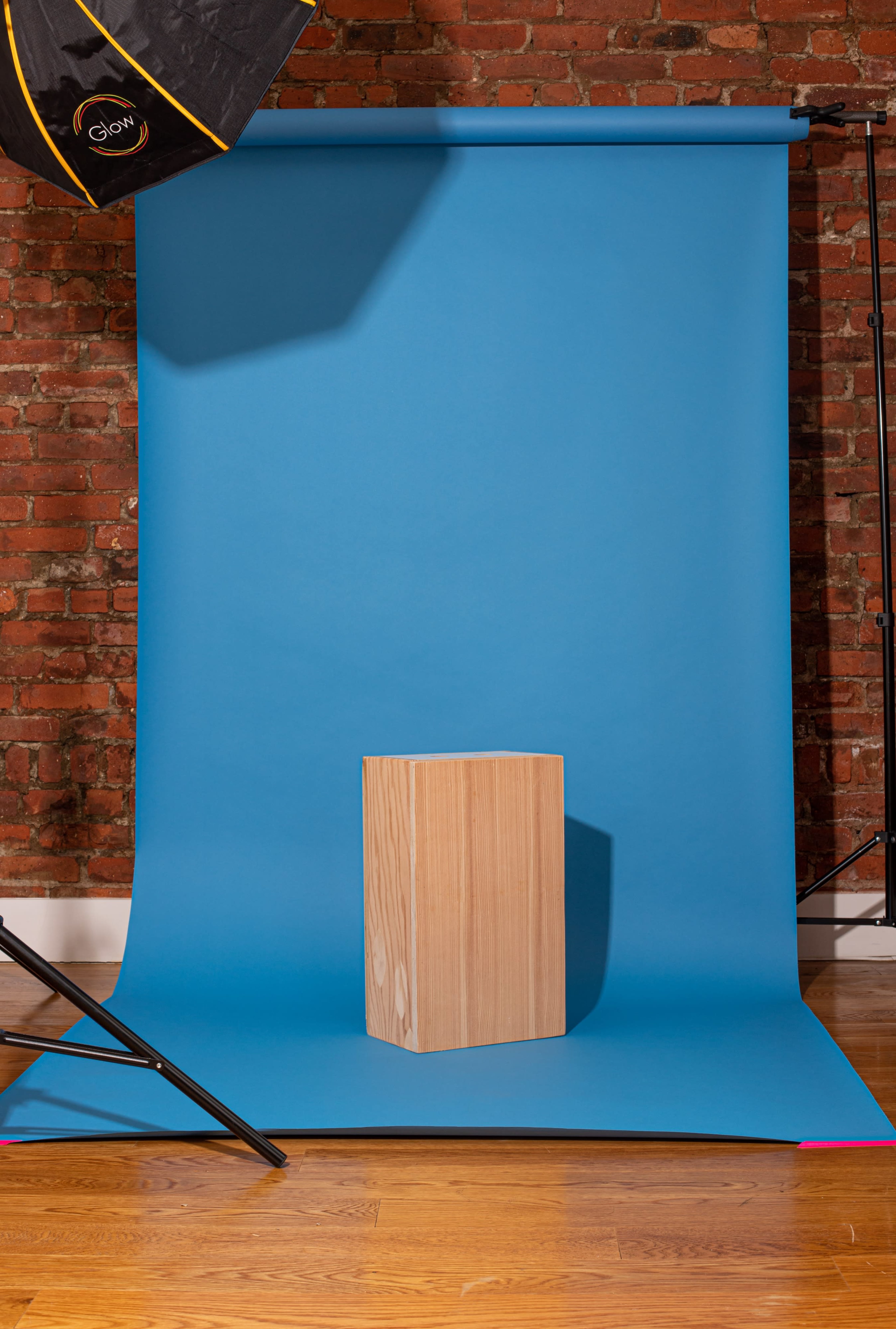 A wooden block placed on a blue backdrop in a studio with brick walls.