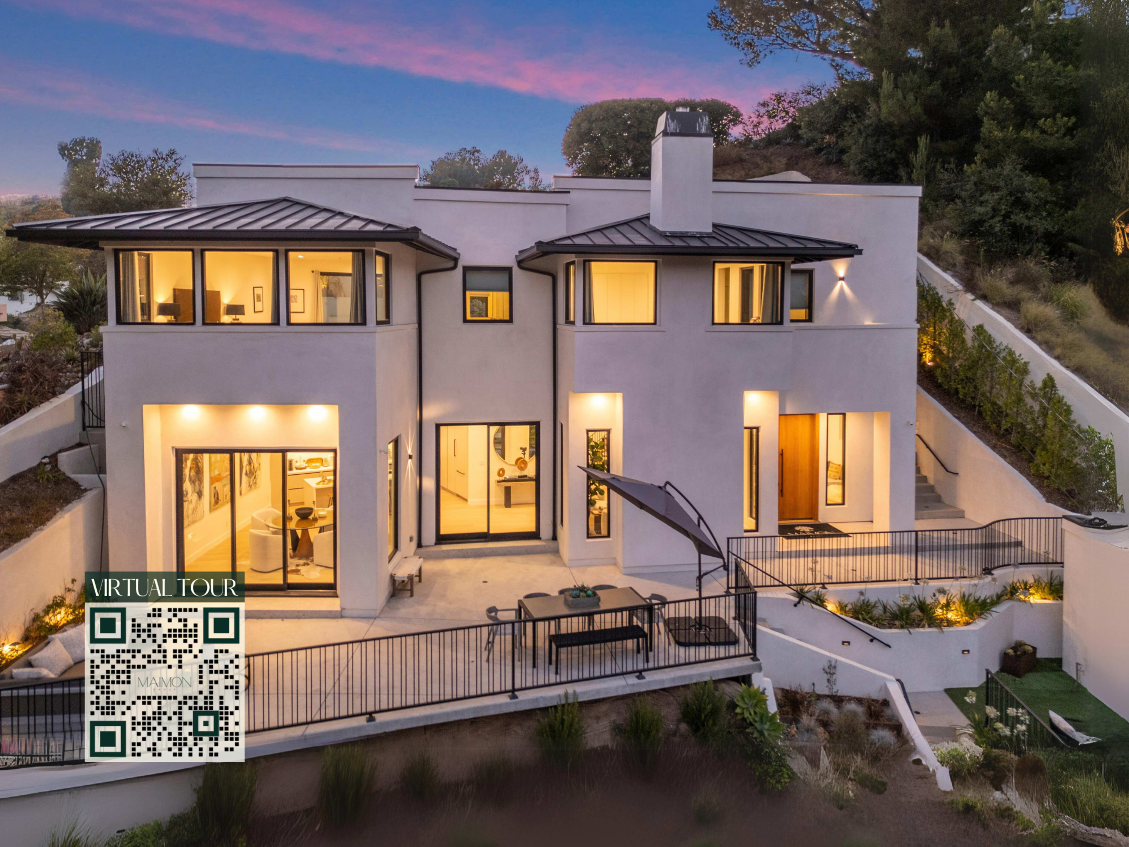 A modern two-story house with a spacious patio, large windows, and a landscaped yard is shown at dusk.