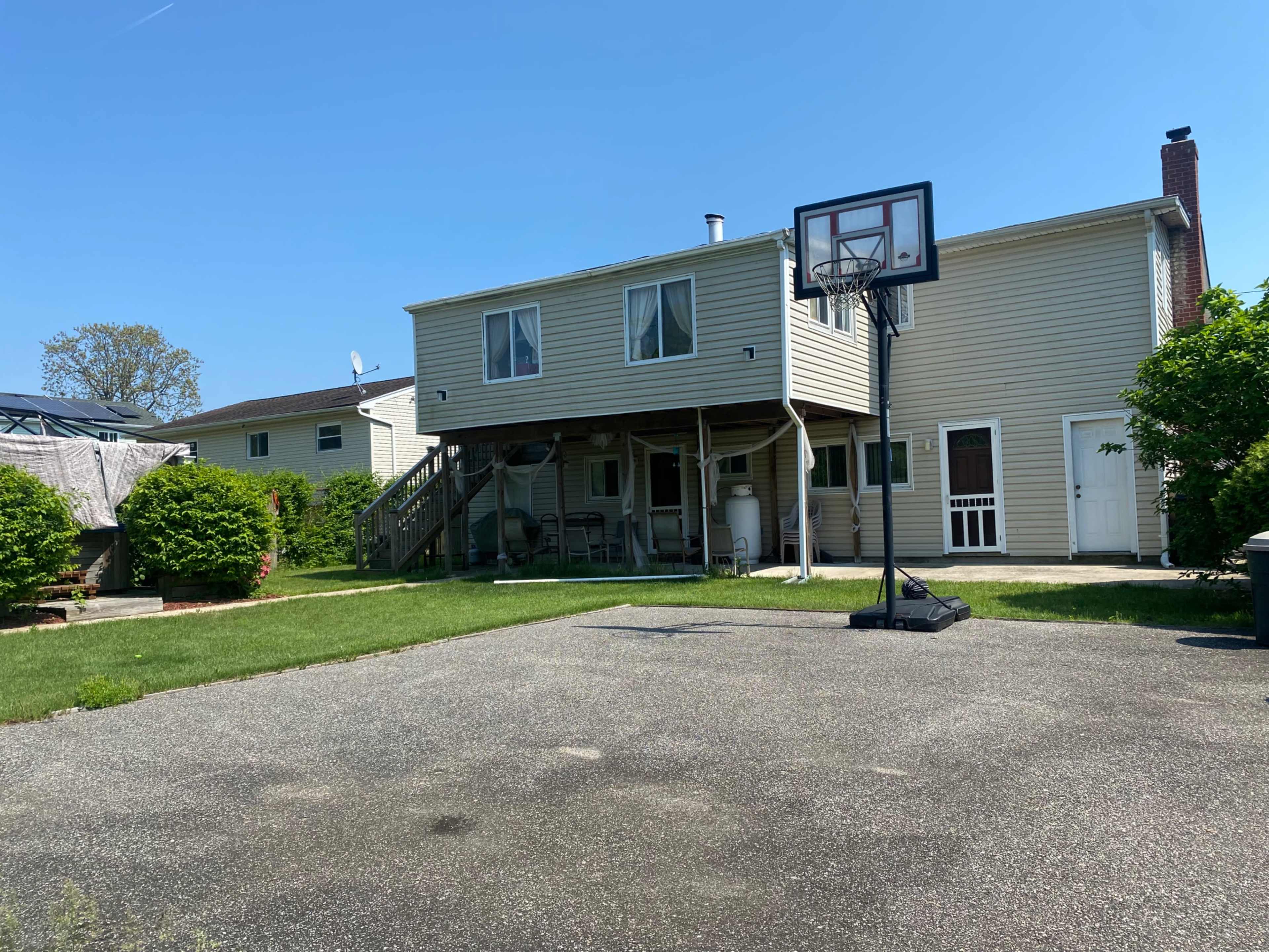 A two-story house with a basketball hoop in the driveway and a grassy lawn.