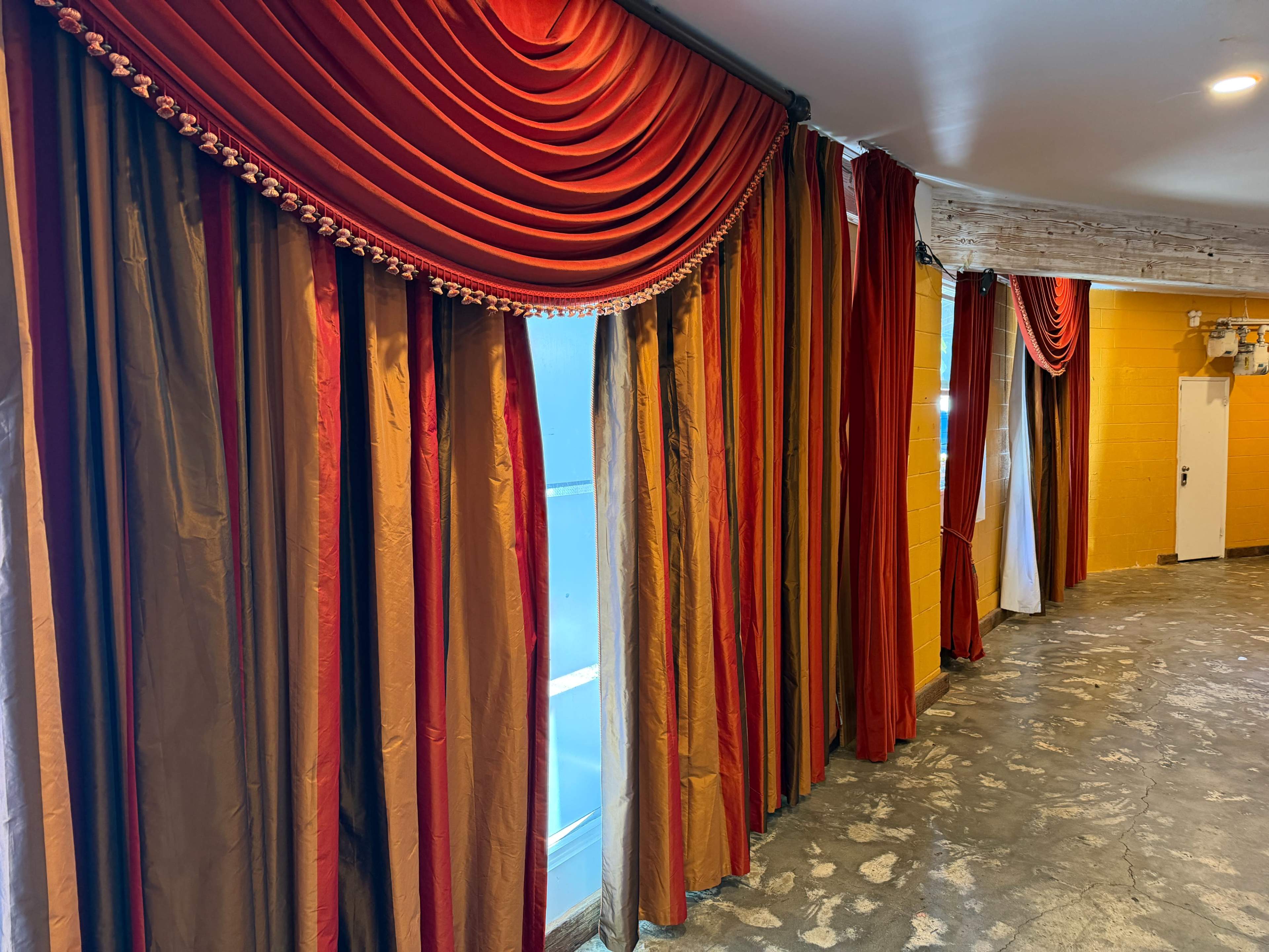A hallway is lined with ornate curtains in shades of red and gold.