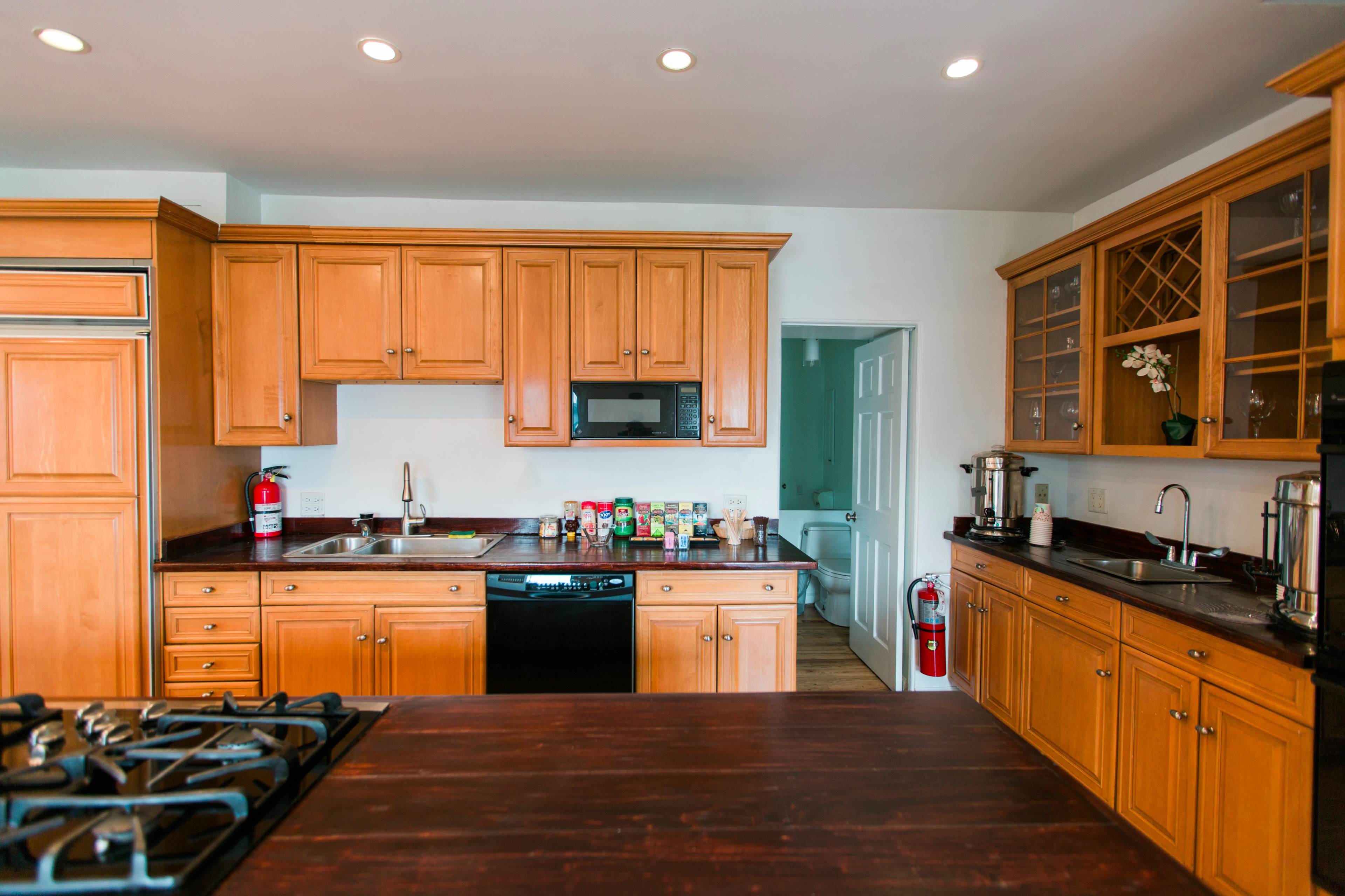 The image shows a kitchen with wooden cabinets, a black dishwasher, and a countertop with various kitchen items.