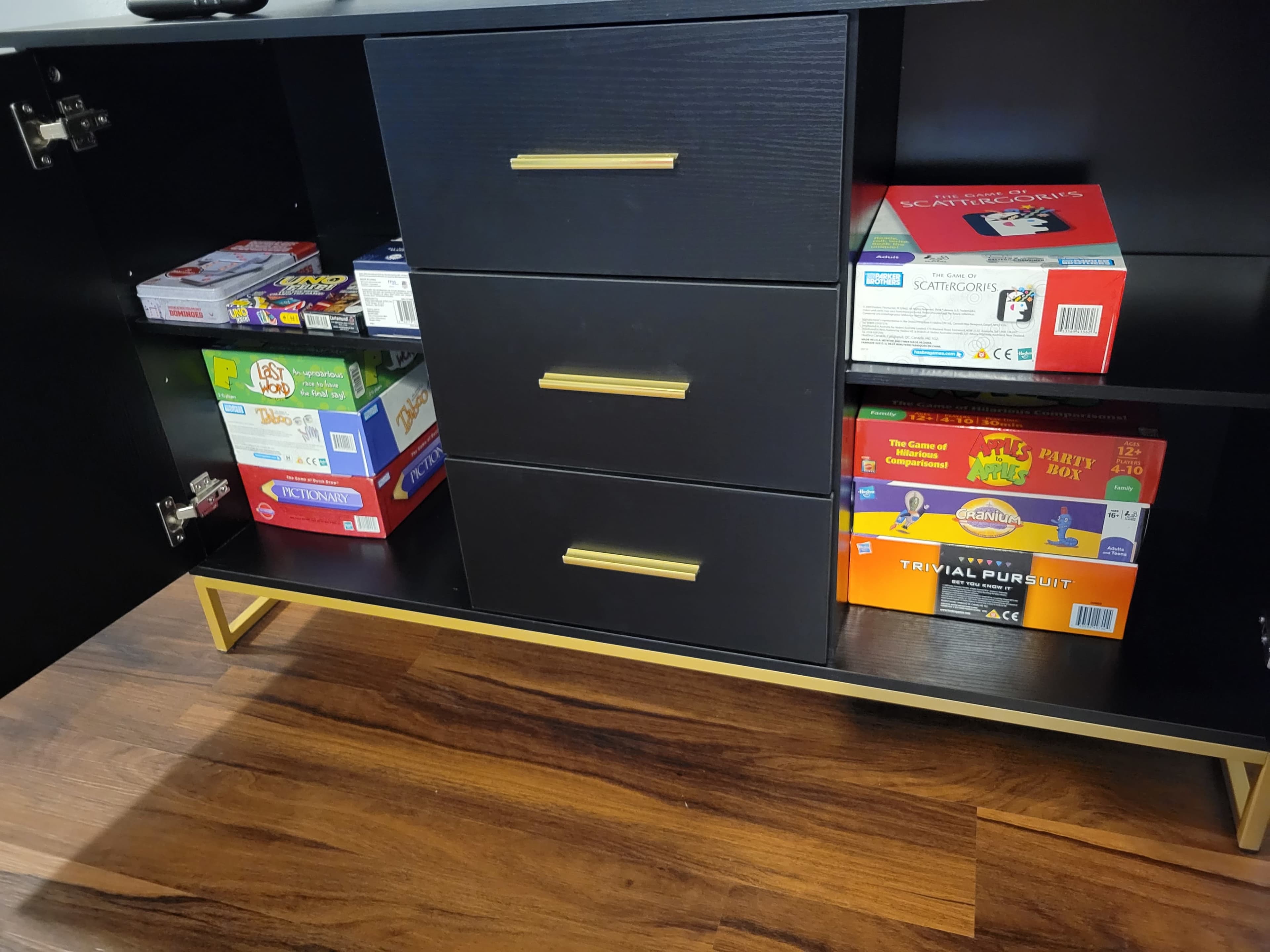 A storage unit with three drawers and various board games neatly stacked on the shelves beside them.