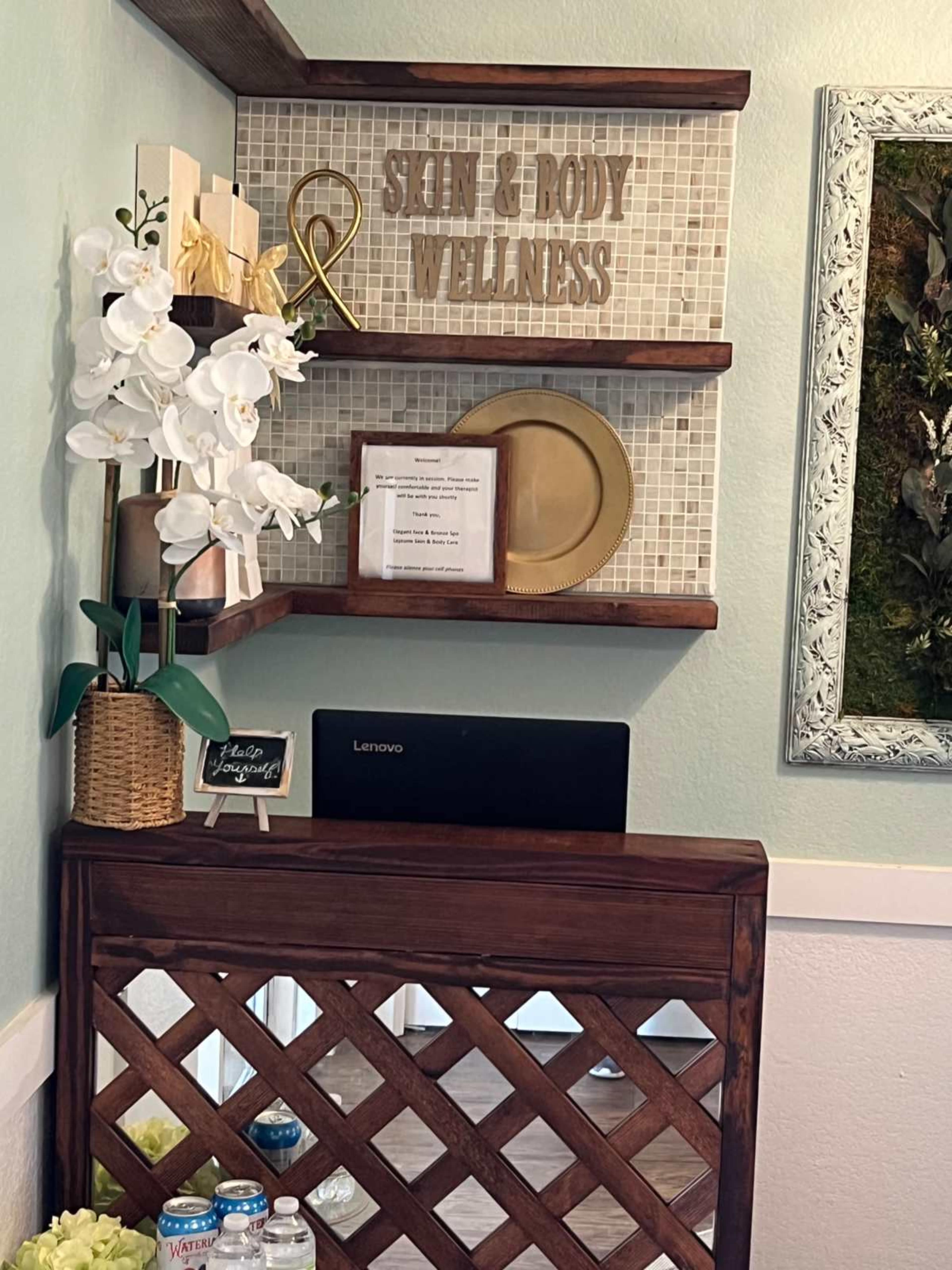 The image shows a small wellness area with shelves displaying decor items, a sign that reads "Skin & Body Wellness," and a wooden partition.