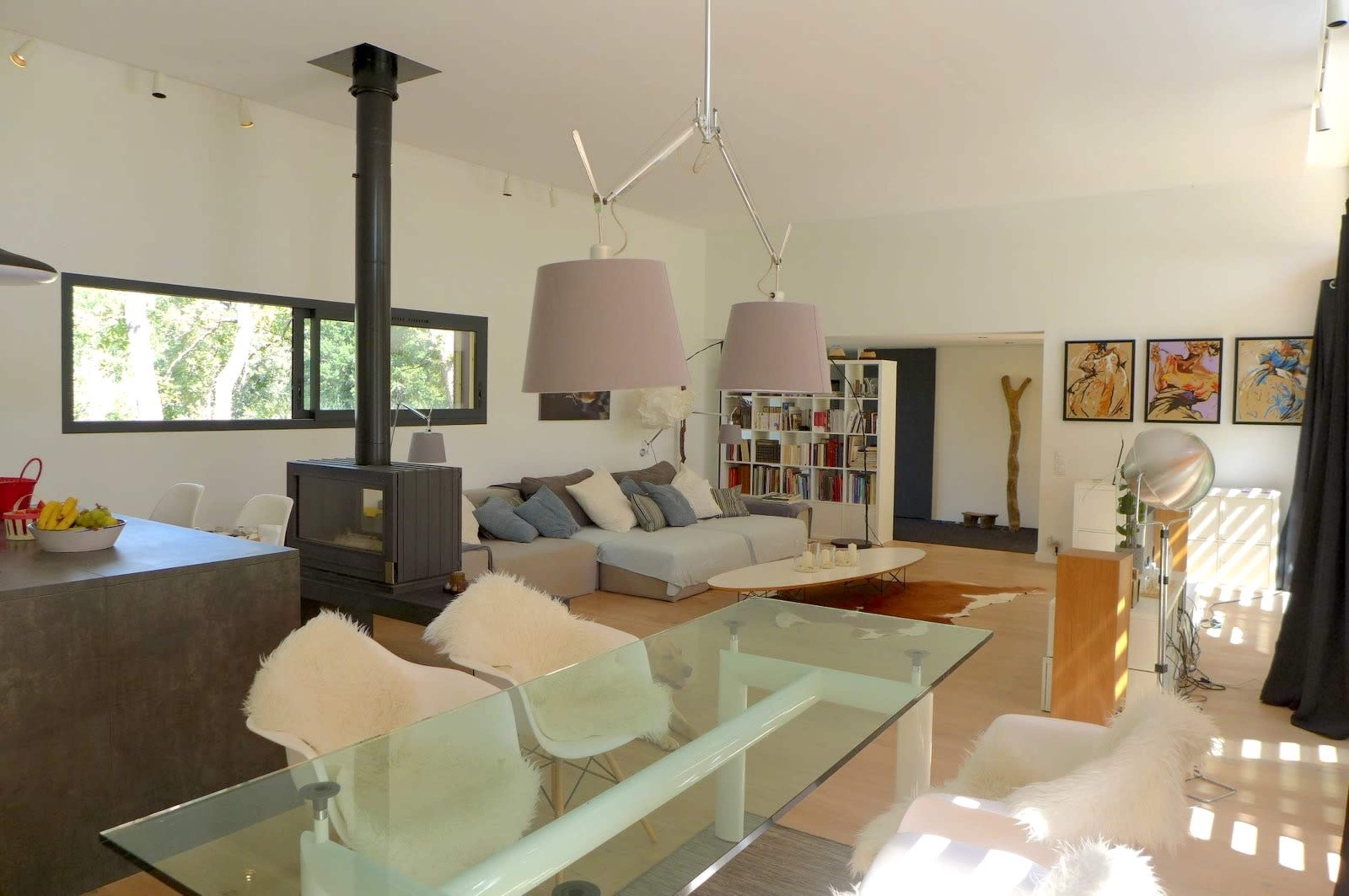 A modern living space with a dining area, a cozy seating arrangement, and large windows allowing natural light to fill the room.