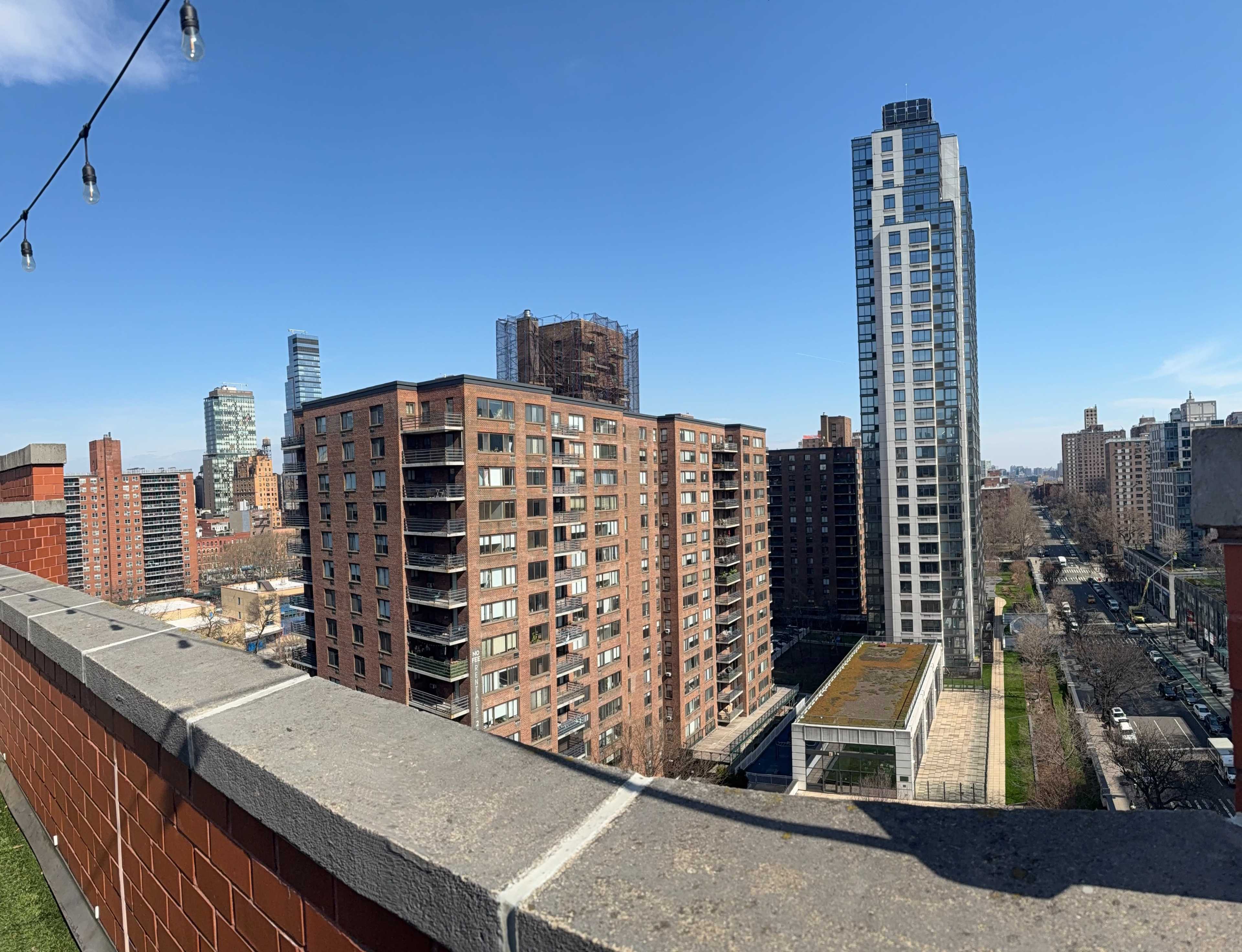 The image shows a rooftop view of urban buildings, including high-rises and mid-rise structures, under a clear blue sky.