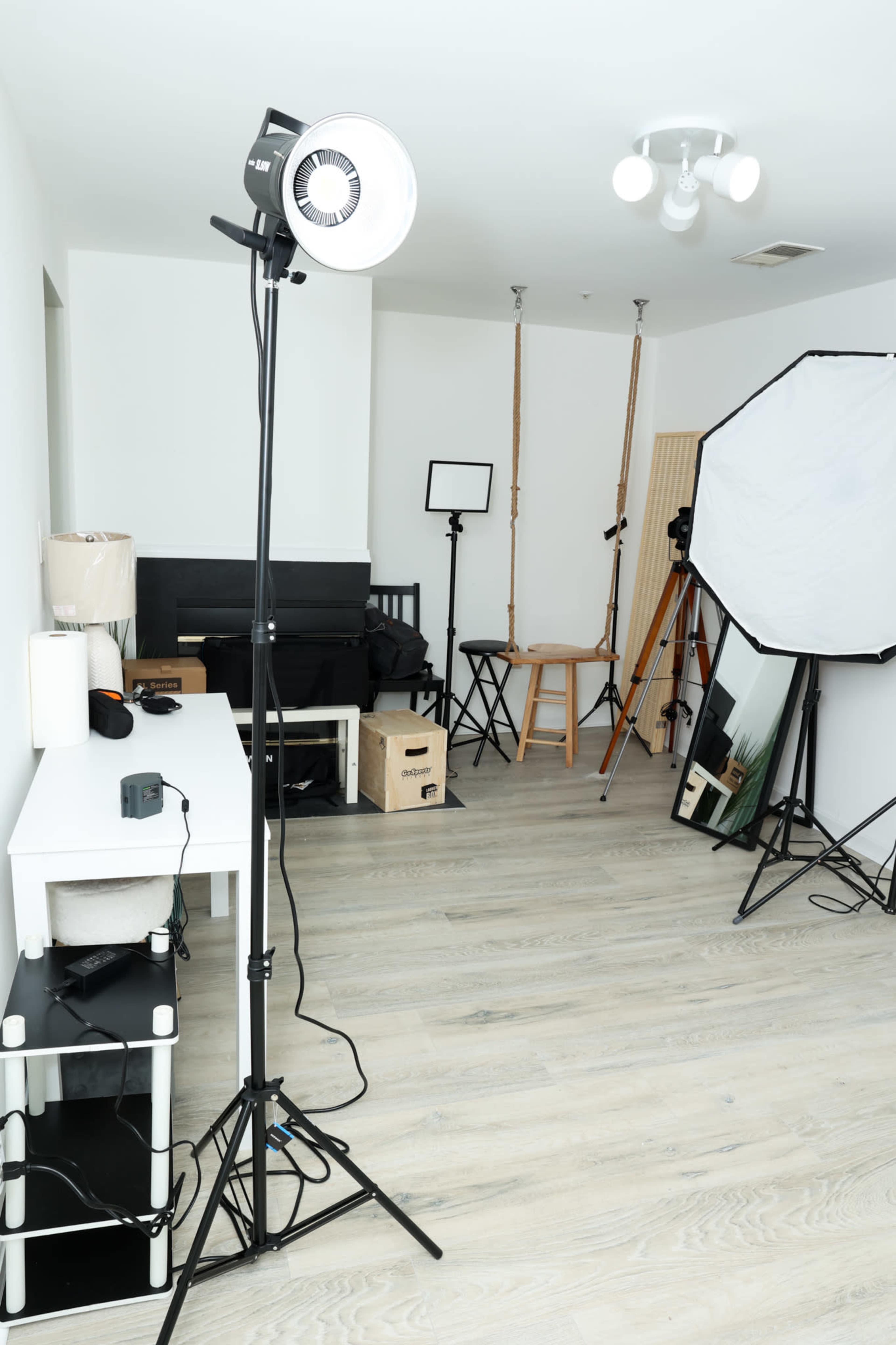 A well-lit studio space with various photography equipment, including tripods, light sources, and a backdrop.