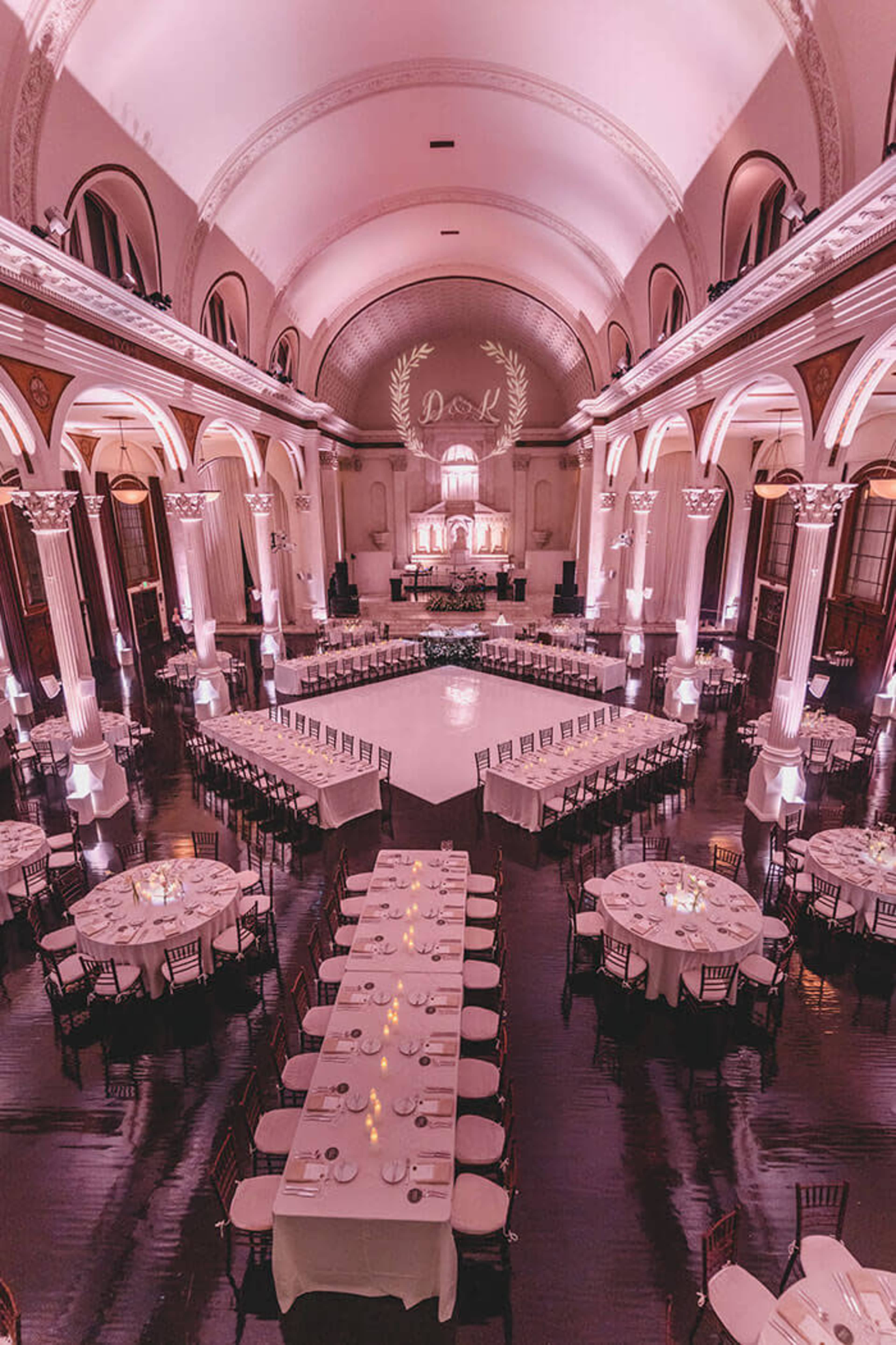 The image shows an elegantly decorated banquet hall with a large circular dance area surrounded by neatly arranged tables, all under soft lighting.