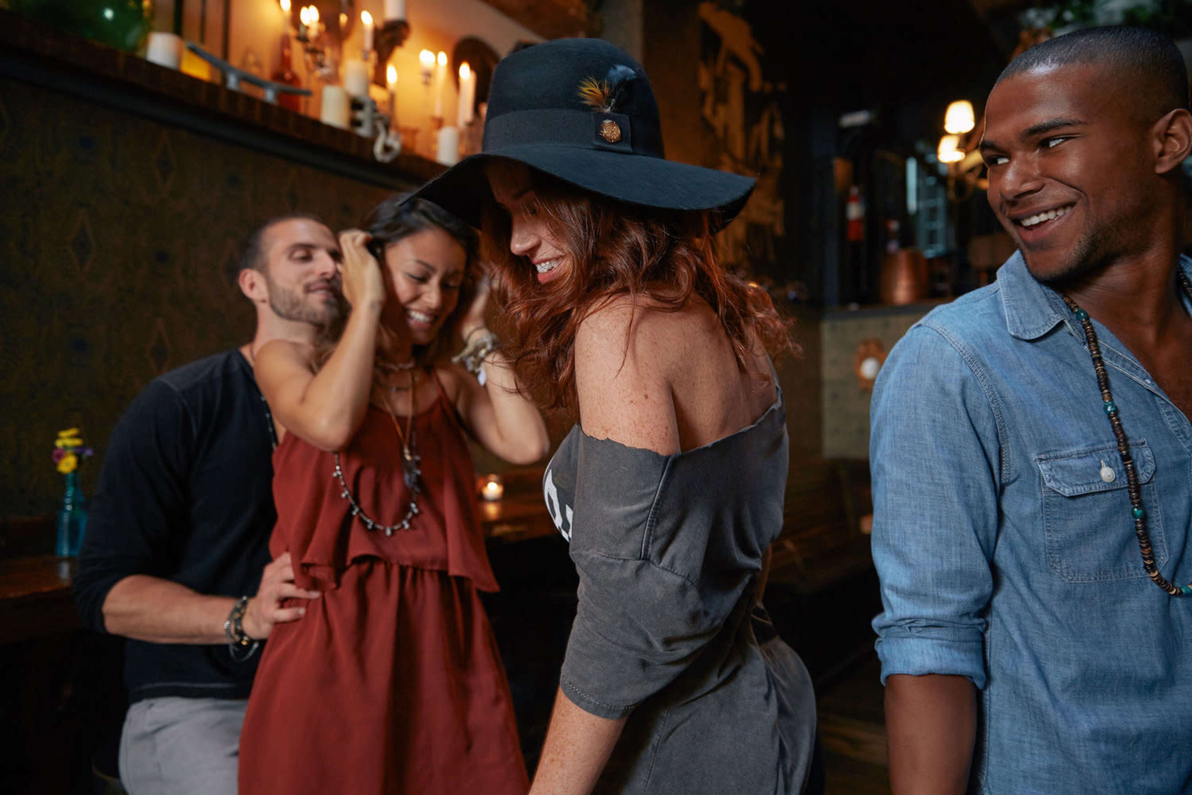 A group of four friends dances and enjoys themselves in a lively bar setting.
