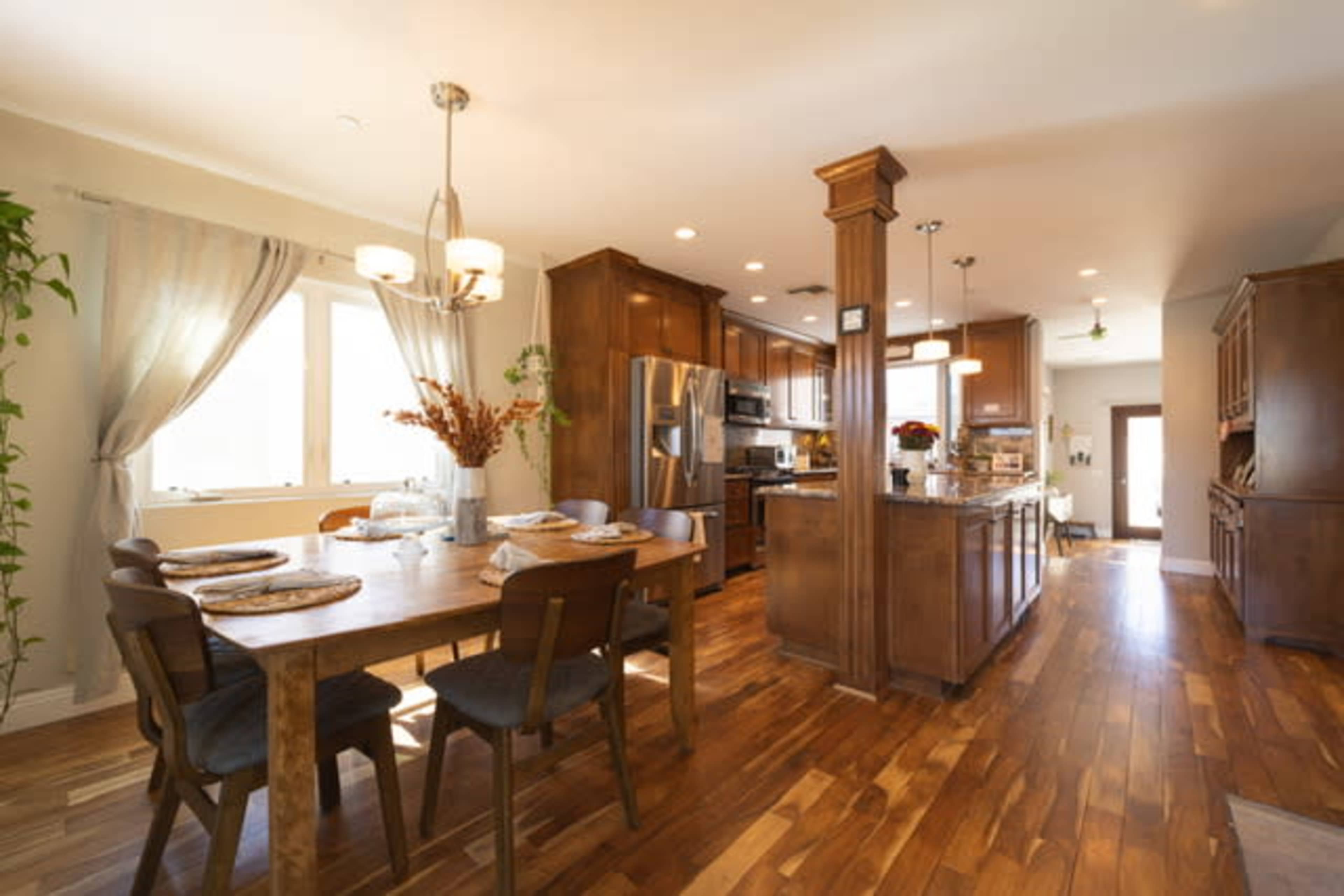 A spacious kitchen and dining area with wooden cabinets, a large table, and hardwood flooring.