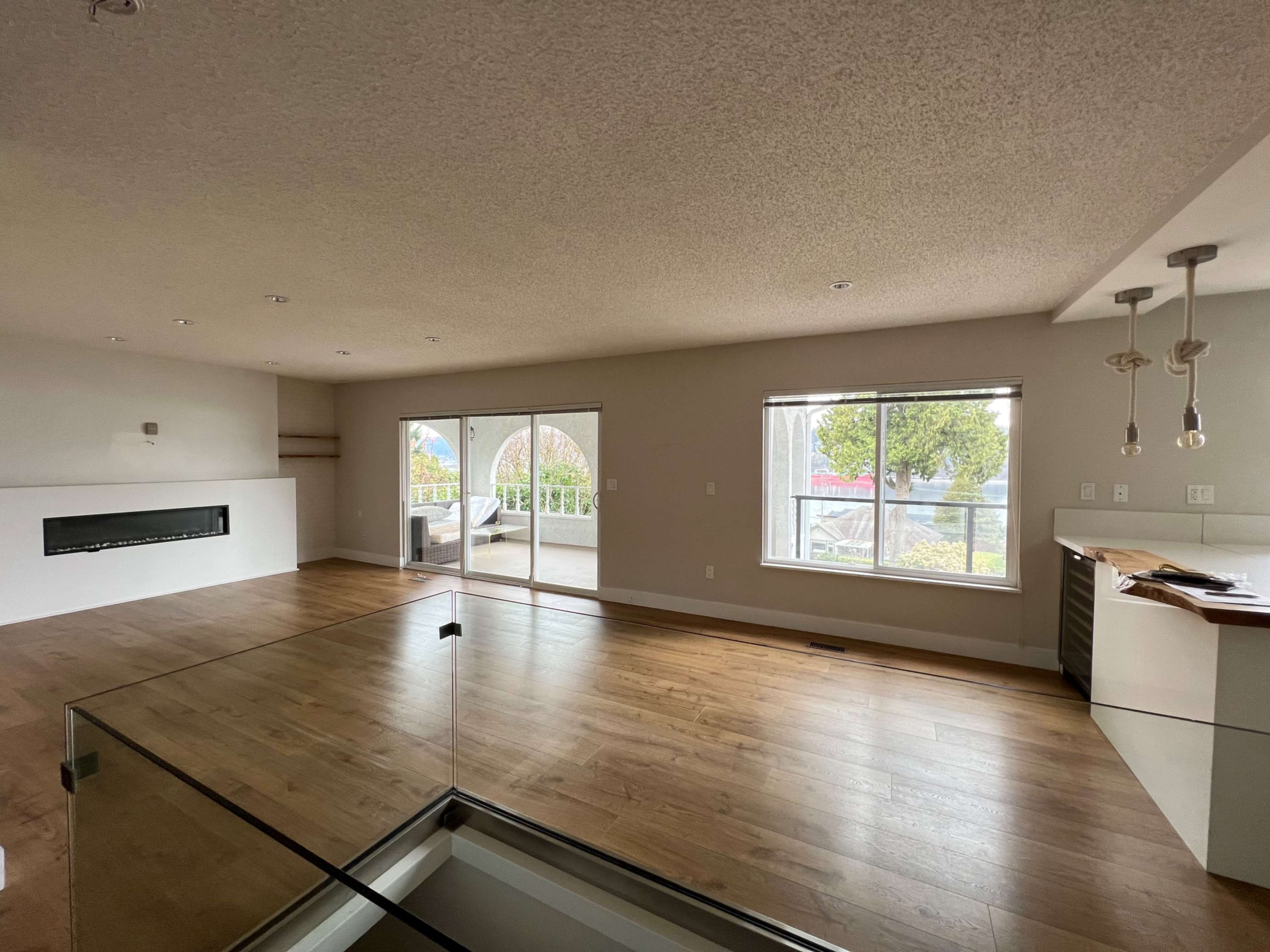 A spacious living area with large windows, hardwood flooring, and modern lighting fixtures.
