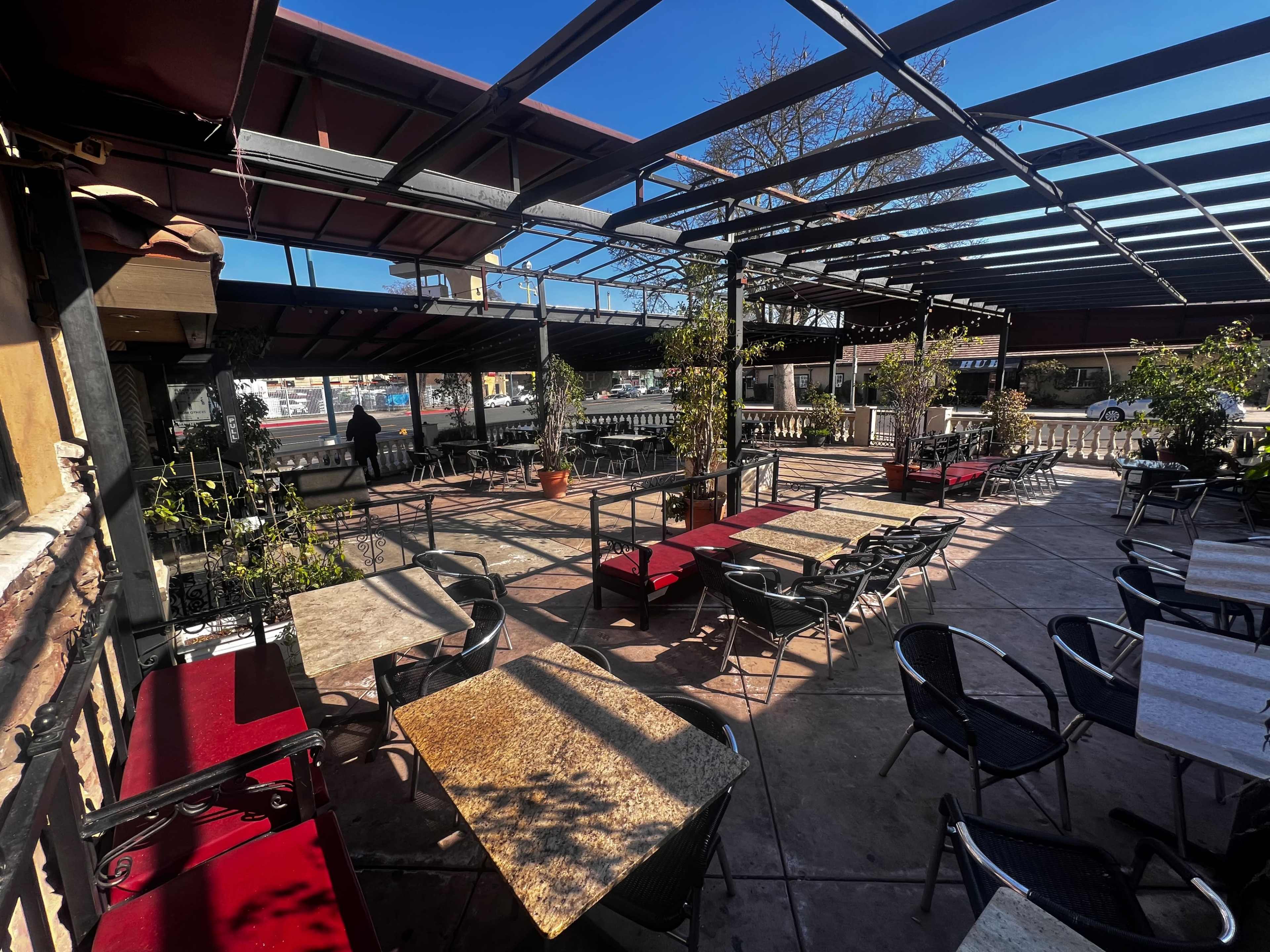 A spacious rooftop restaurant features empty tables and chairs under a clear blue sky.