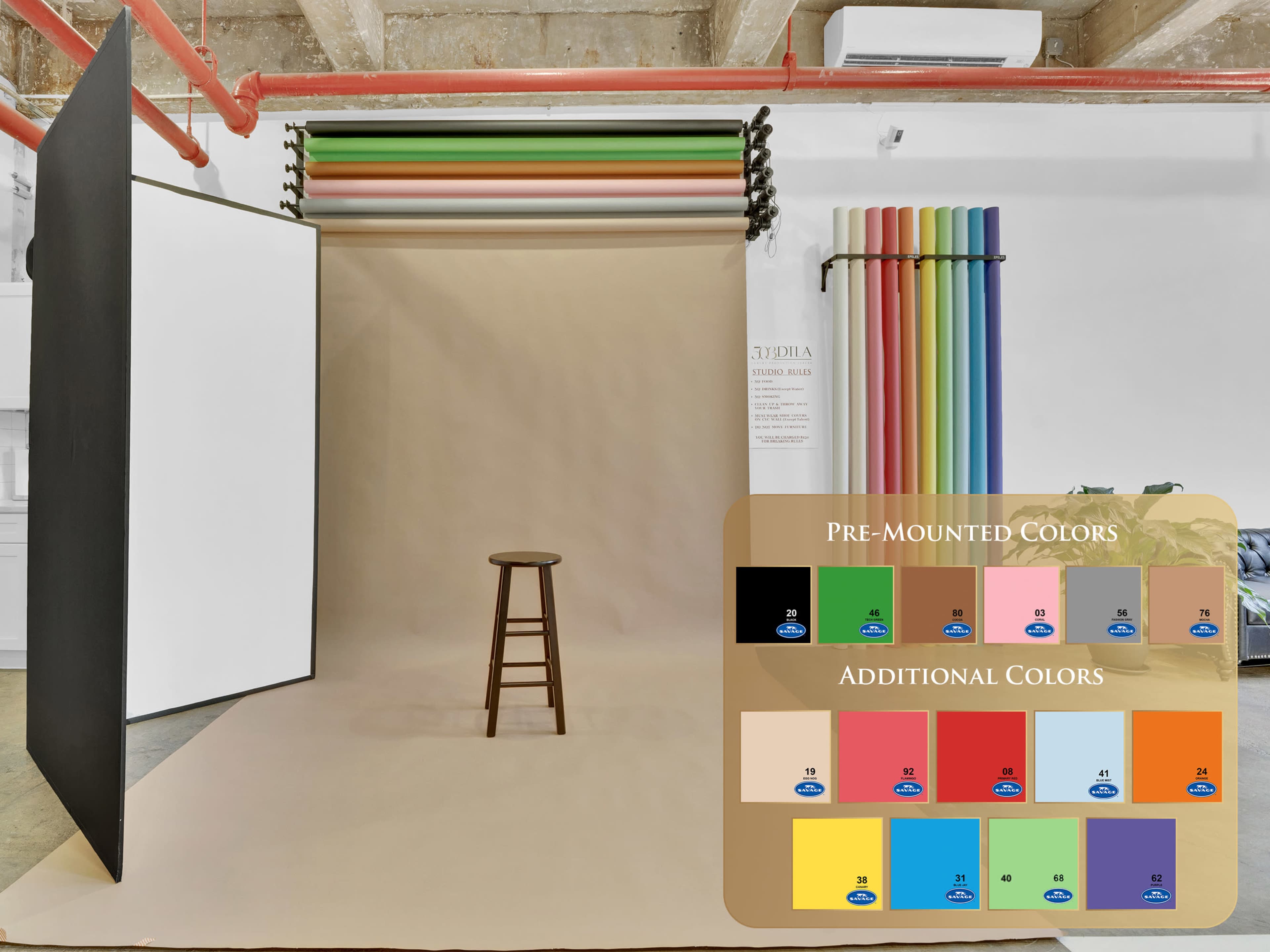 The image shows a photography studio setup with a stool in front of a backdrop made of various colored rolls and a neutral-colored floor.