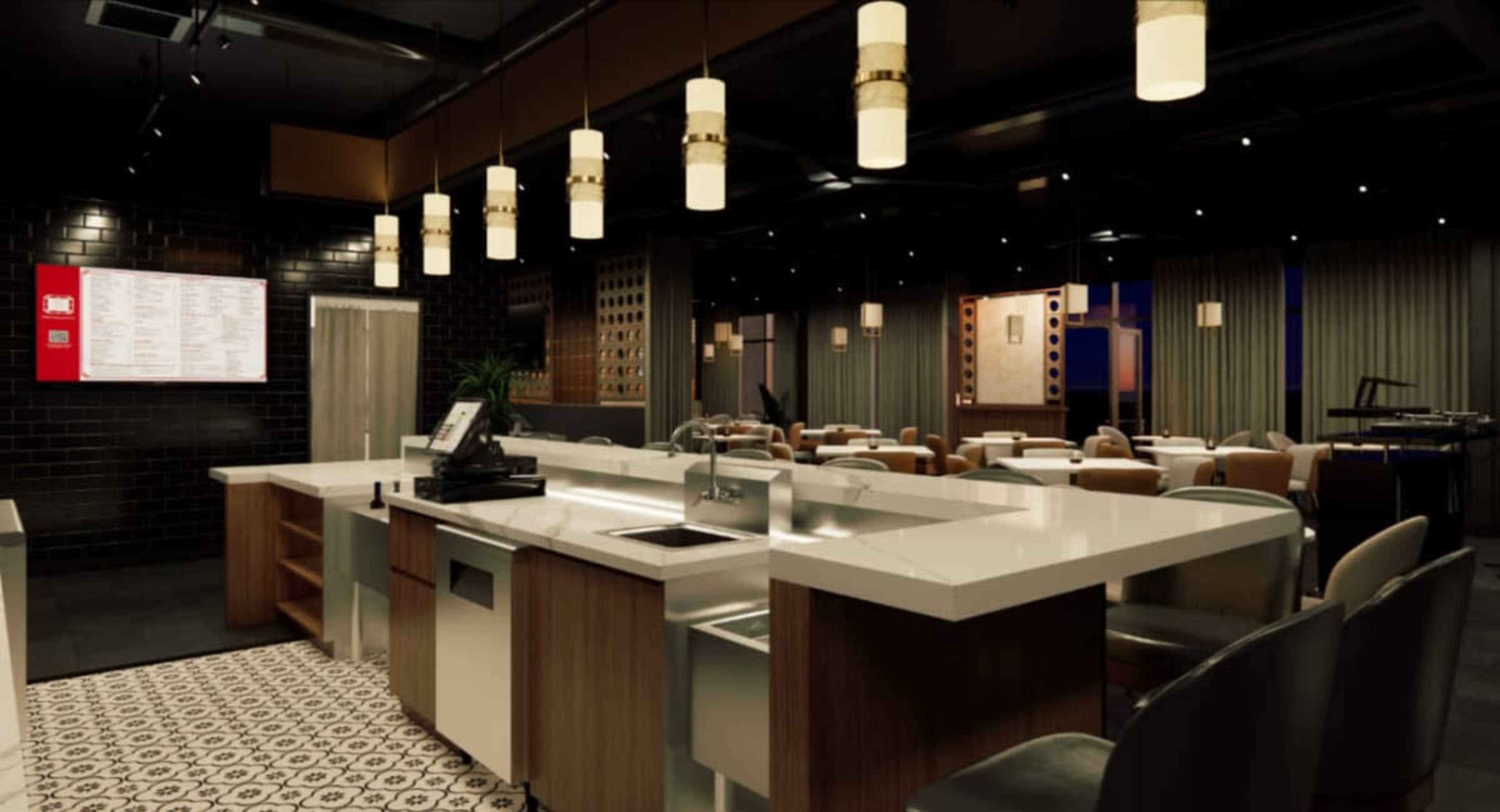 The image shows a modern restaurant interior featuring an open kitchen area with a bar and seating for diners, illuminated by pendant lights.
