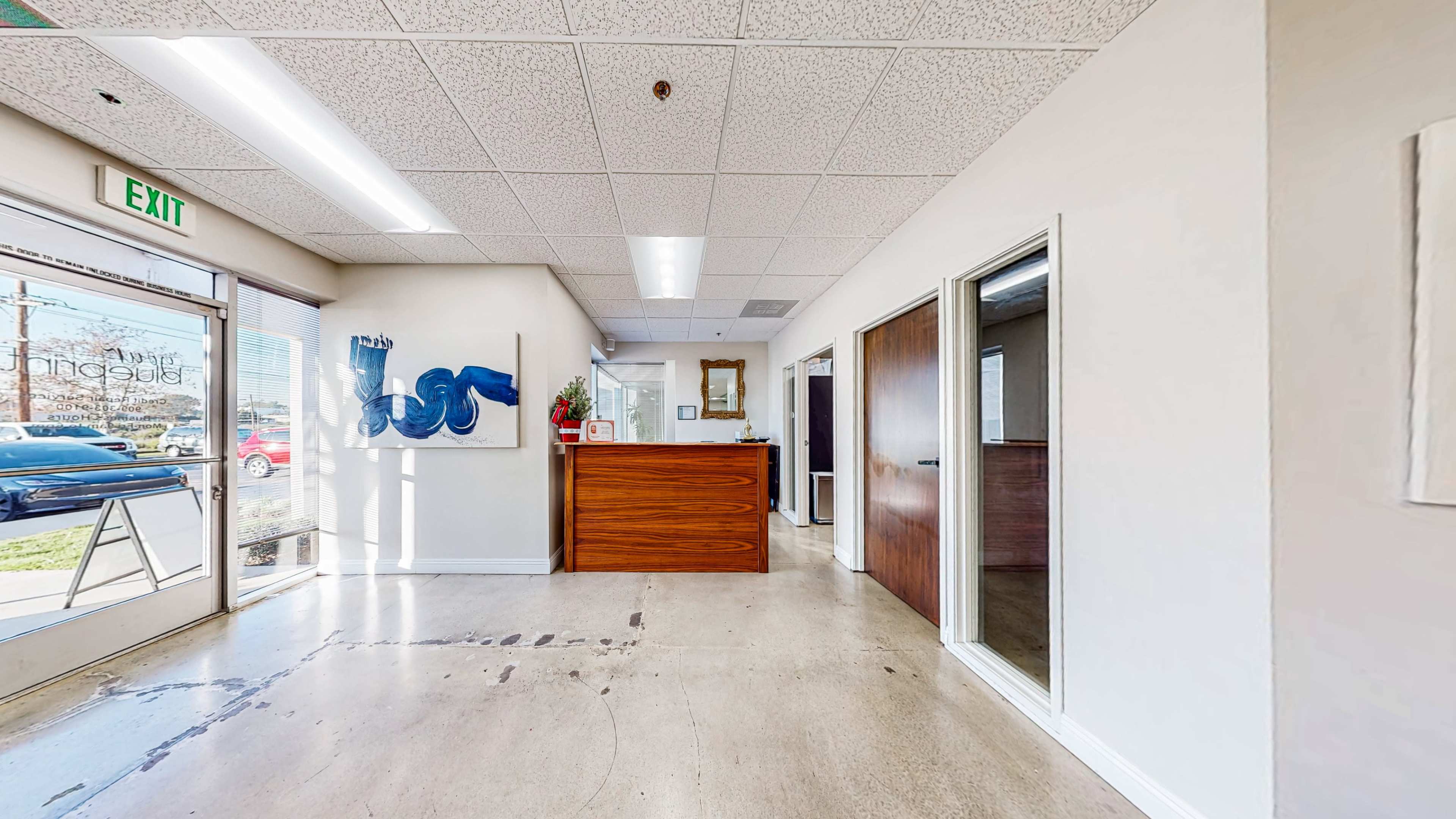 The image shows a clean, brightly lit reception area with a wooden reception desk and adjoining office spaces.