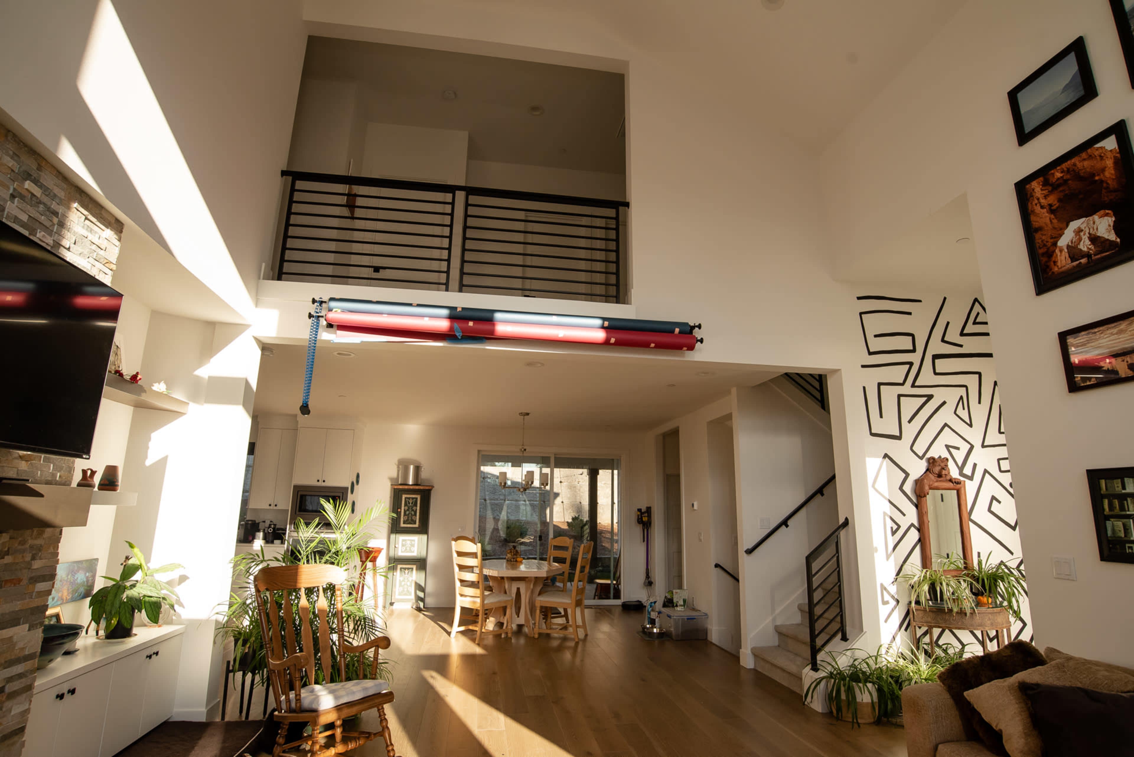 A bright, modern living space with a high ceiling, an open layout, and a dining area visible in the background.