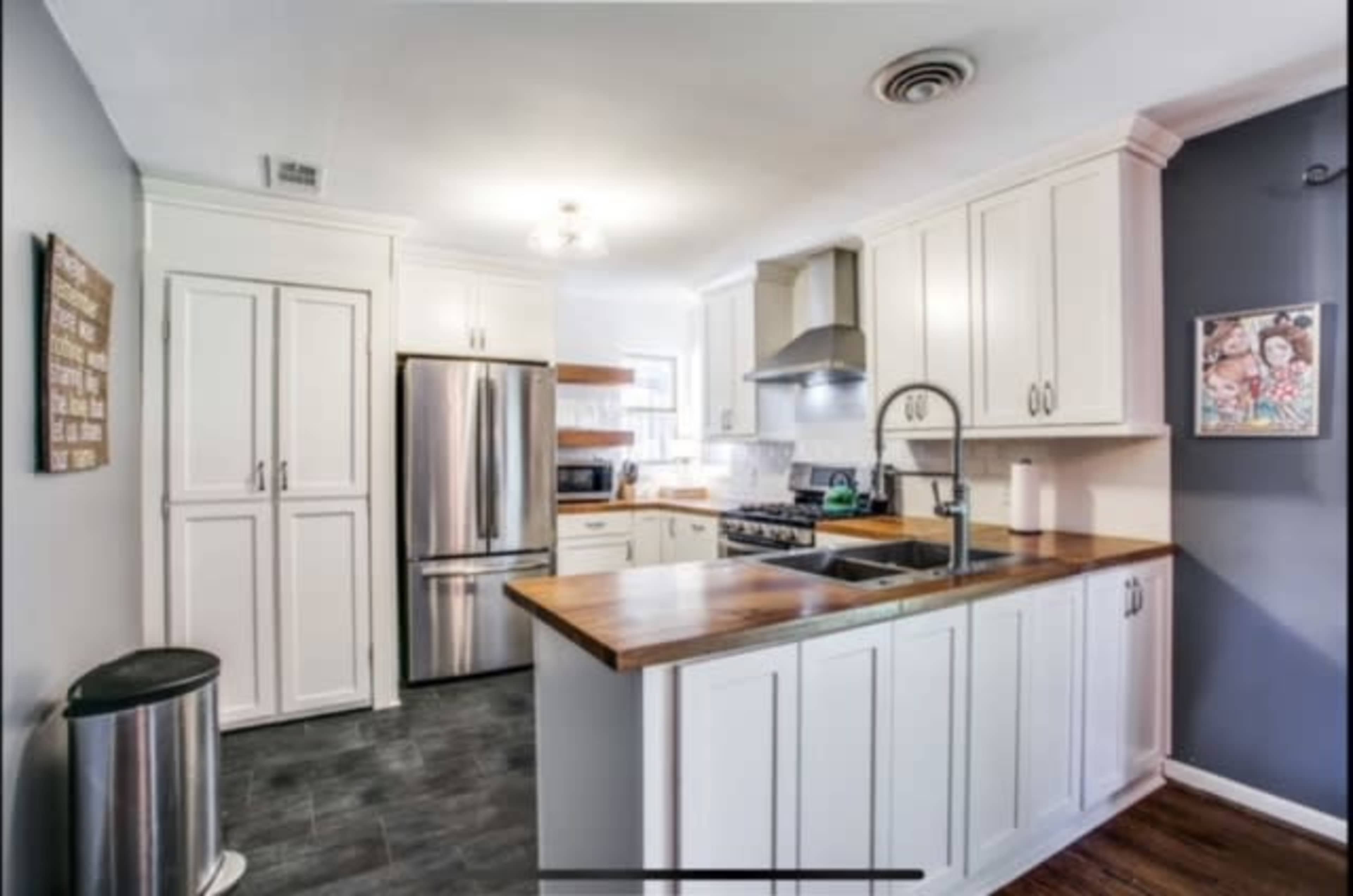 The kitchen features white cabinetry, stainless steel appliances, and a wooden countertop with an island.