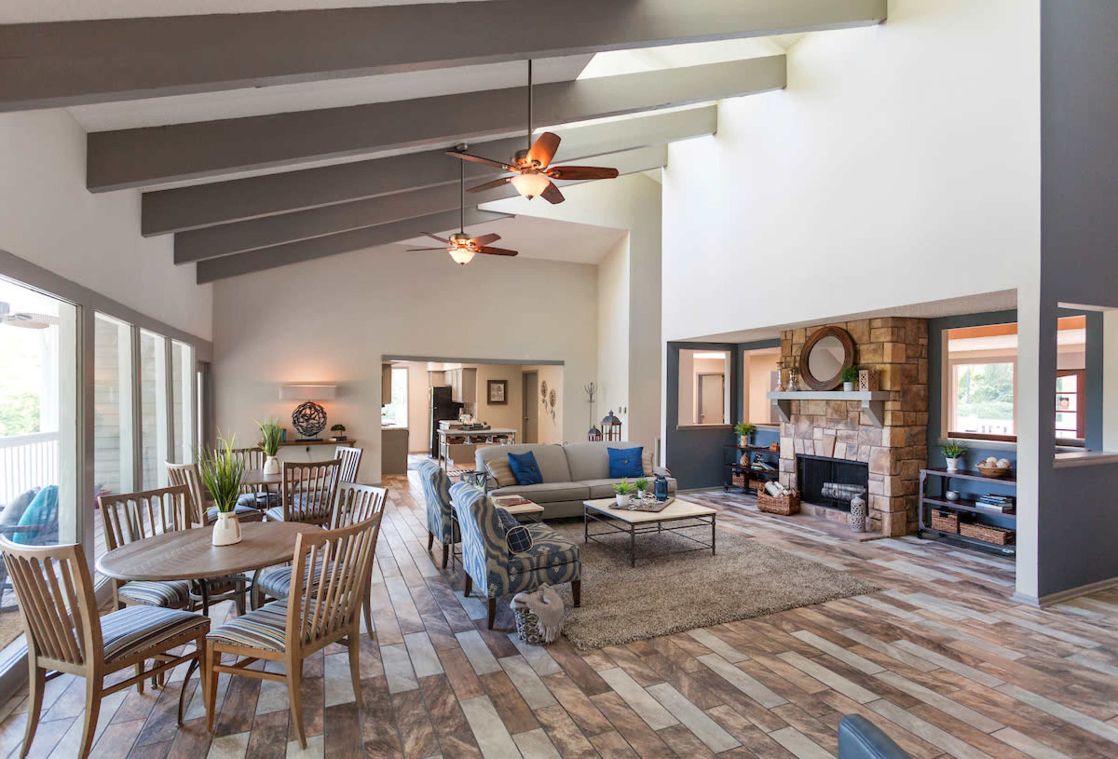 A spacious living area featuring large windows, a stone fireplace, and a dining table set for six.