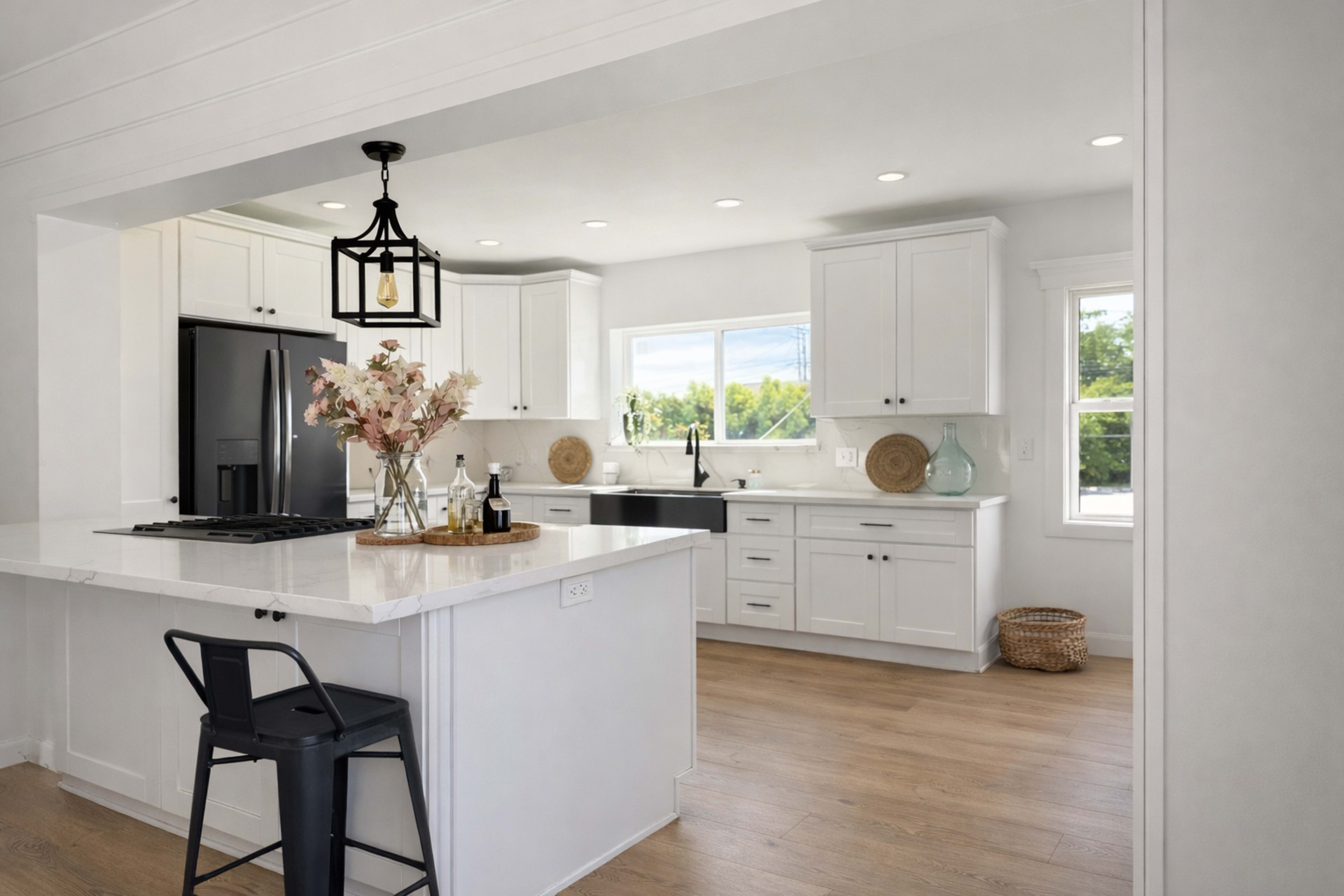 The image shows a modern kitchen with white cabinets, a large island, and a window that provides natural light.