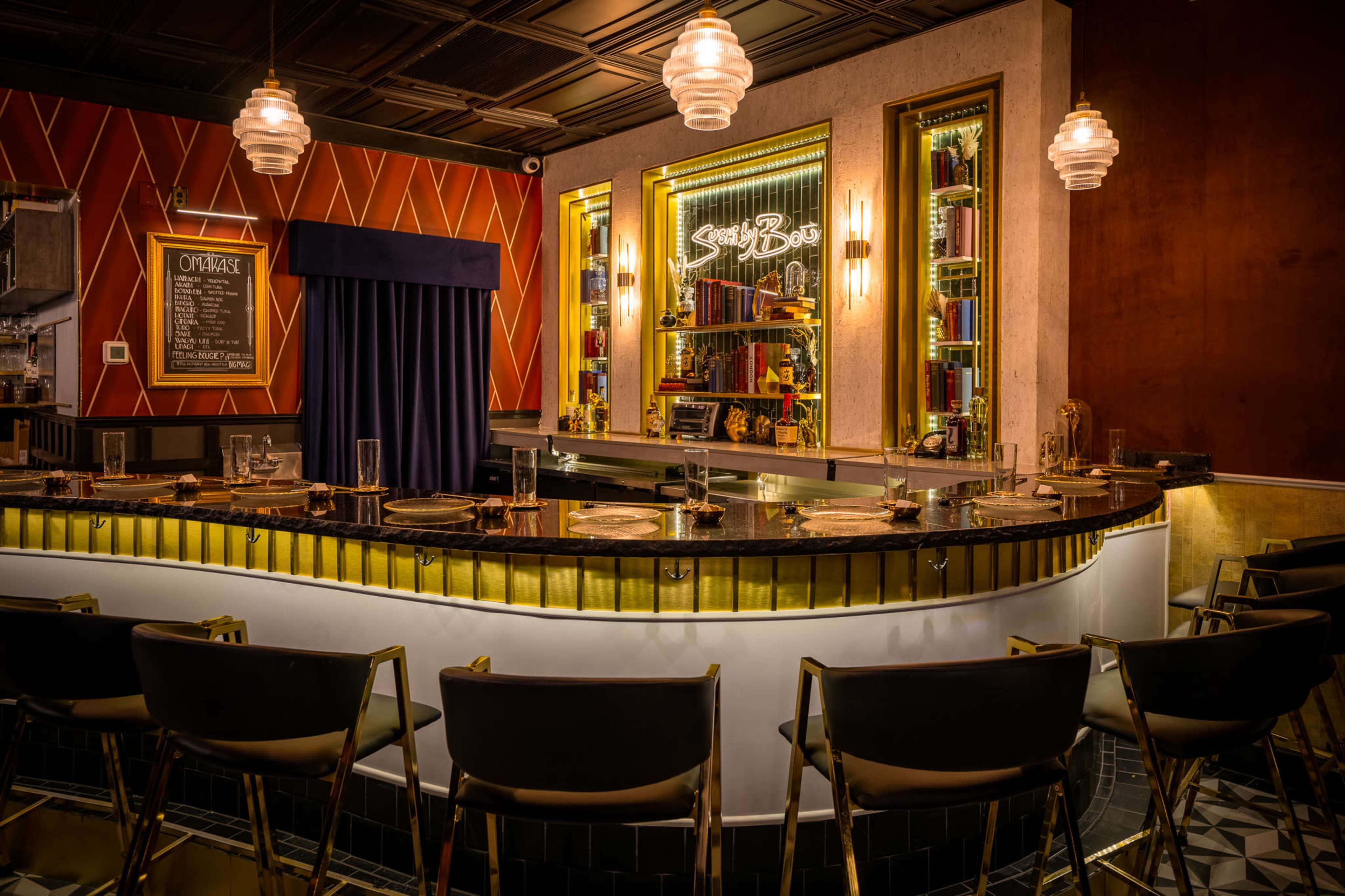 The image shows a stylish bar with a curved counter, illuminated shelves filled with bottles, and a decorative backdrop featuring a velvet curtain and elegant lighting fixtures.